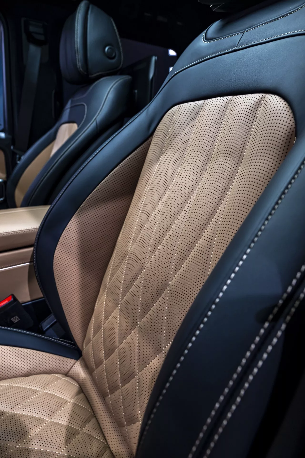 Detailný pohľad na interiér Mercedes-Benz G-Klasse 2024 so zameraním na sedadlo z kvalitnej kože vo dvoch odtieňoch s diamantovým prešívaním a zlepšenou bočnou podporou