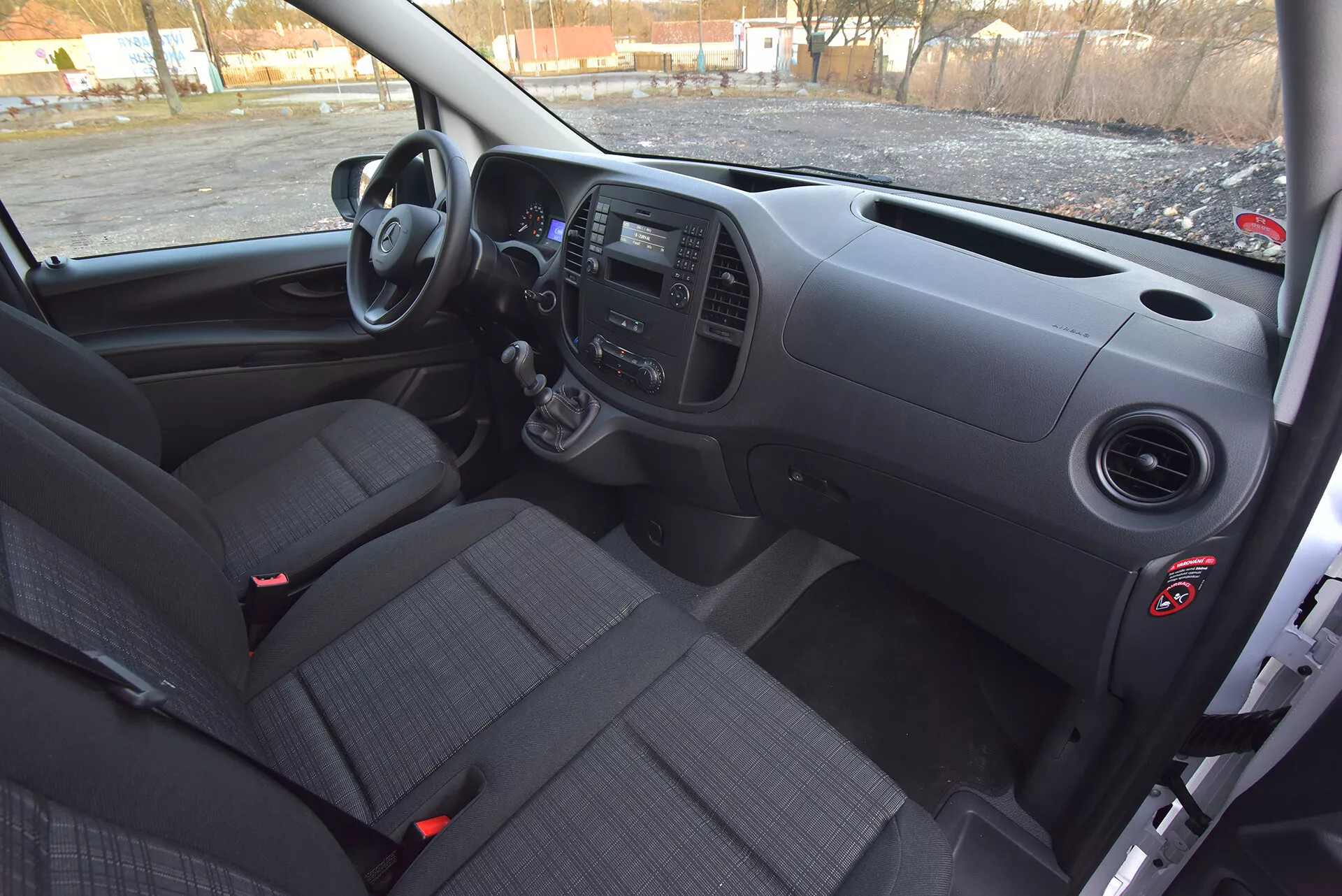 Interiér Mercedes-Benz Vito Tourer z roku 2014 z pohľadu vodiča s predným palubným panelom, manuálnou prevodovkou, ovládacími panelmi a sedadlami s poťahom