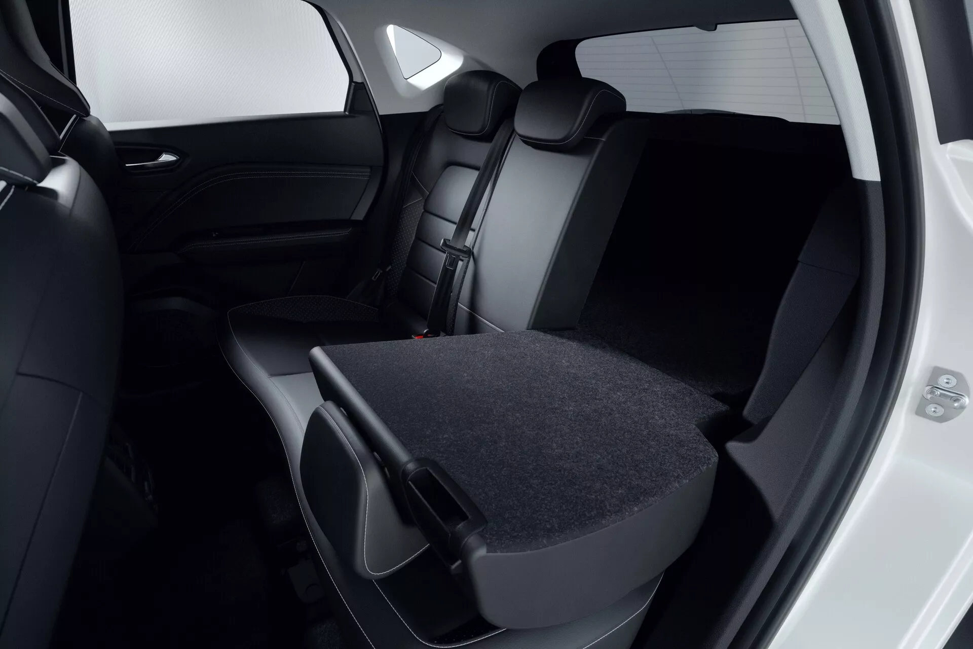 Detailný pohľad na zadný interiér Mitsubishi ASX 2023 (2. generácia). Zameranie na tmavé, kožené alebo koženkové sedadlá, kde je pravé zadné sedadlo sklopné, čo ukazuje flexibilitu nákladu. Zadné dvere sú otvorené, odhaľujú zodpovedajúci tmavý interiér a tónované okná. Moderný, minimalistický dizajn je evidentný v čiernej alebo tmavosivej farebnej palete. Obrázok zdôrazňuje skladovaciu kapacitu vozidla a záväzok k bezpečnosti s viditeľnými opierkami hlavy a bezpečnostnými pásmi.
