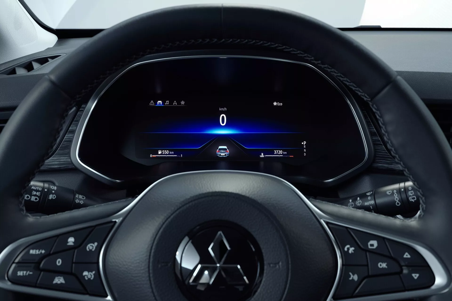 Interiér Mitsubishi ASX 2023 (2. generácia) z pohľadu vodiča, zameraný na trojramenný multifunkčný volant s tlačidlami pre médiá, telefón, tempomat a s logom výrobcu. Za ním je plne digitálny prístrojový panel s tachometrom ukazujúcim 0 km/h, smerovkami, časom a počítadlom najazdených kilometrov. Kokpitový štýl naznačuje dizajn orientovaný na vodiča so štíhlym a moderným vzhľadom, ktorý kladie dôraz na technológie a jednoduchý prístup k informáciám a ovládaniu vozidla.