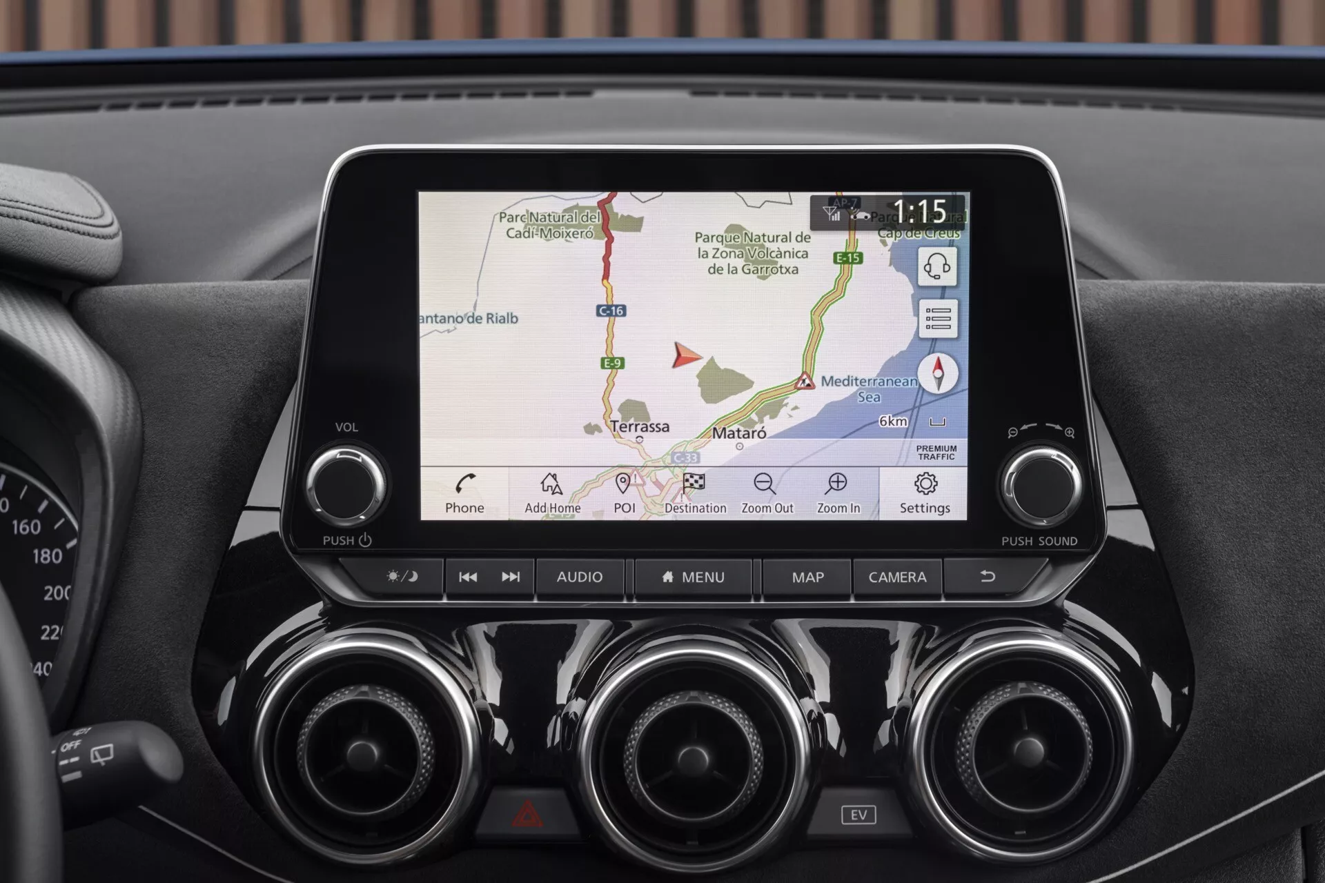 Detailný pohľad na displej infotainmentu a centrálnu palubnú dosku Nissan Juke F16 z roku 2019 s GPS navigáciou, pripojením telefónu, vzduchovými otvormi a ovládacími tlačidlami pre pokročilé technológie a pohodlie