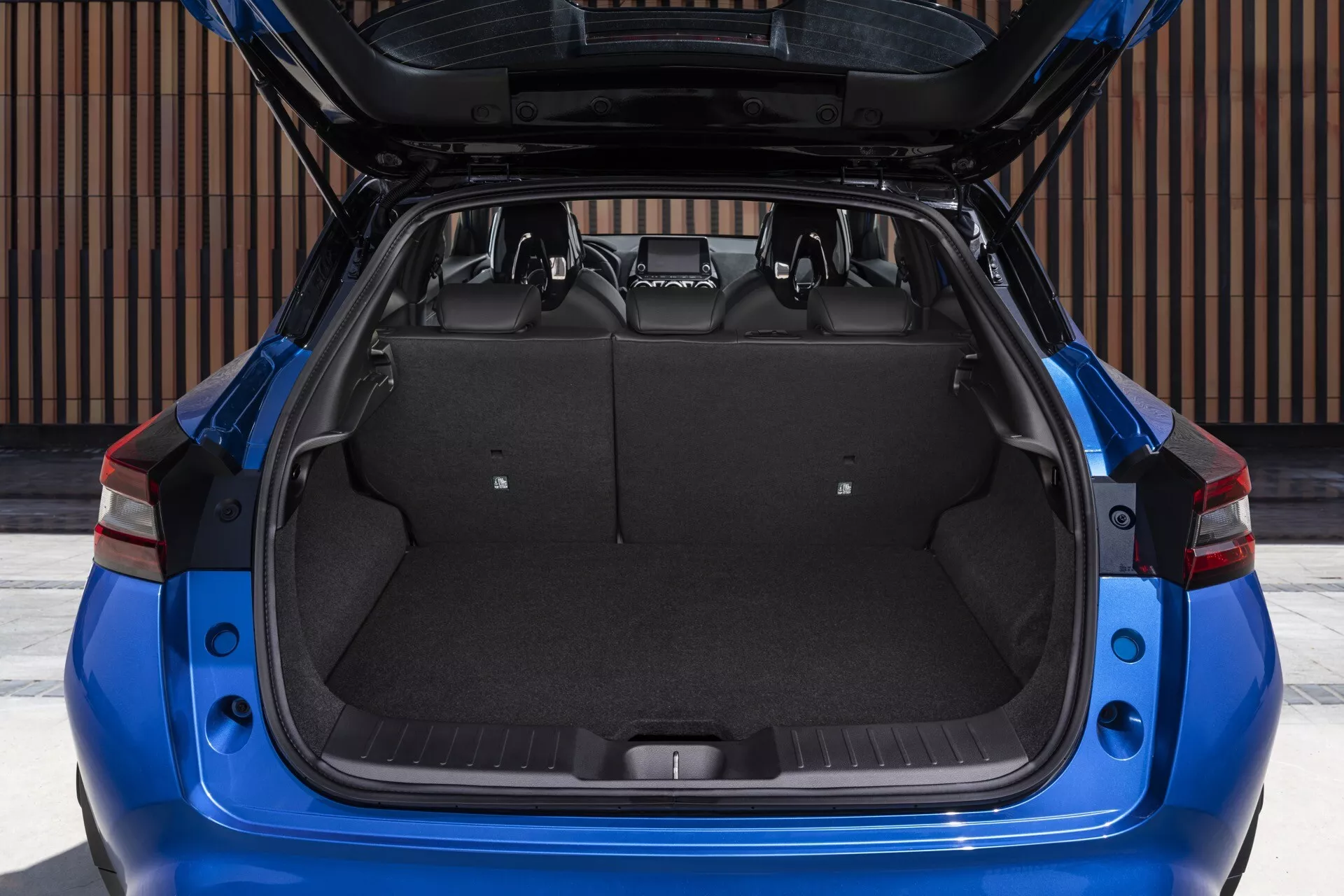 Zadný pohľad na modrý Nissan Juke z roku 2019 F16 s otvoreným kufrom zobrazujúcim nákladový priestor a dizajnové prvky na dennom svetle