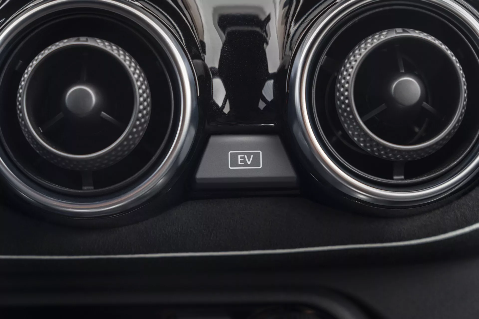 Detailný pohľad na interiér Nissan Juke 2019 (F16) zameraný na ventilačné otvory klimatizácie a tlačidlo EV módu medzi nimi, prezentujúci kontrolu klímy v aute a technológiu elektrických vozidiel.