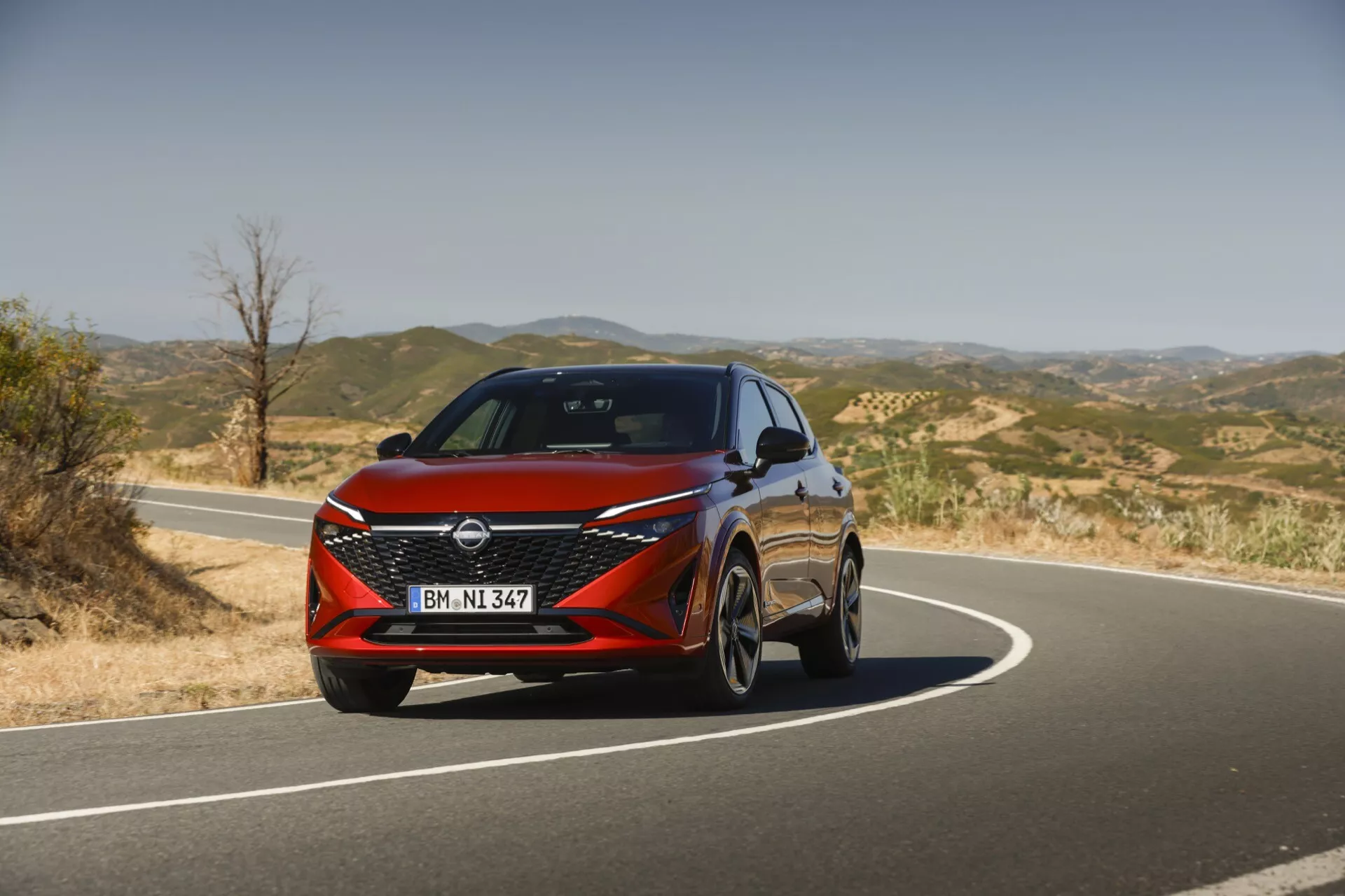 Pohľad spredu na Nissan Qashqai 2024 J12-facelift, ktorý predstavuje moderný dizajn s elegantnými LED svetlometmi, odvážnou prednou maskou vo forme V-motion a dynamickými líniami zdôrazňujúcimi jeho športový a sofistikovaný vzhľad.