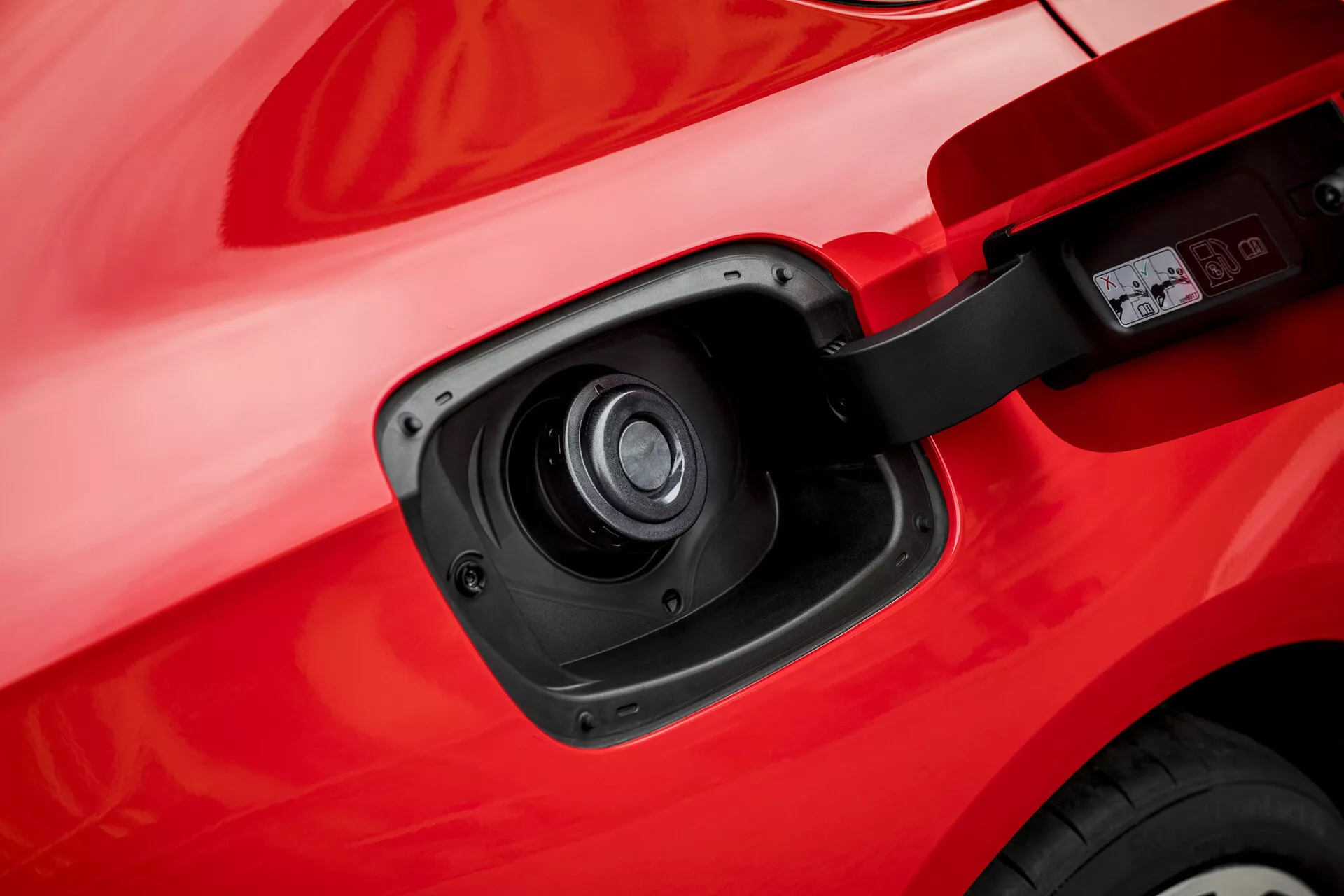 Detailný pohľad na nabíjací port na Opli Insignia z roku 2013 ukazujúci jeho elektrické alebo hybridné schopnosti s detailným pohľadom na otvorené dvere nabíjacieho portu a zásuvku voči červenej karosérii vozidla