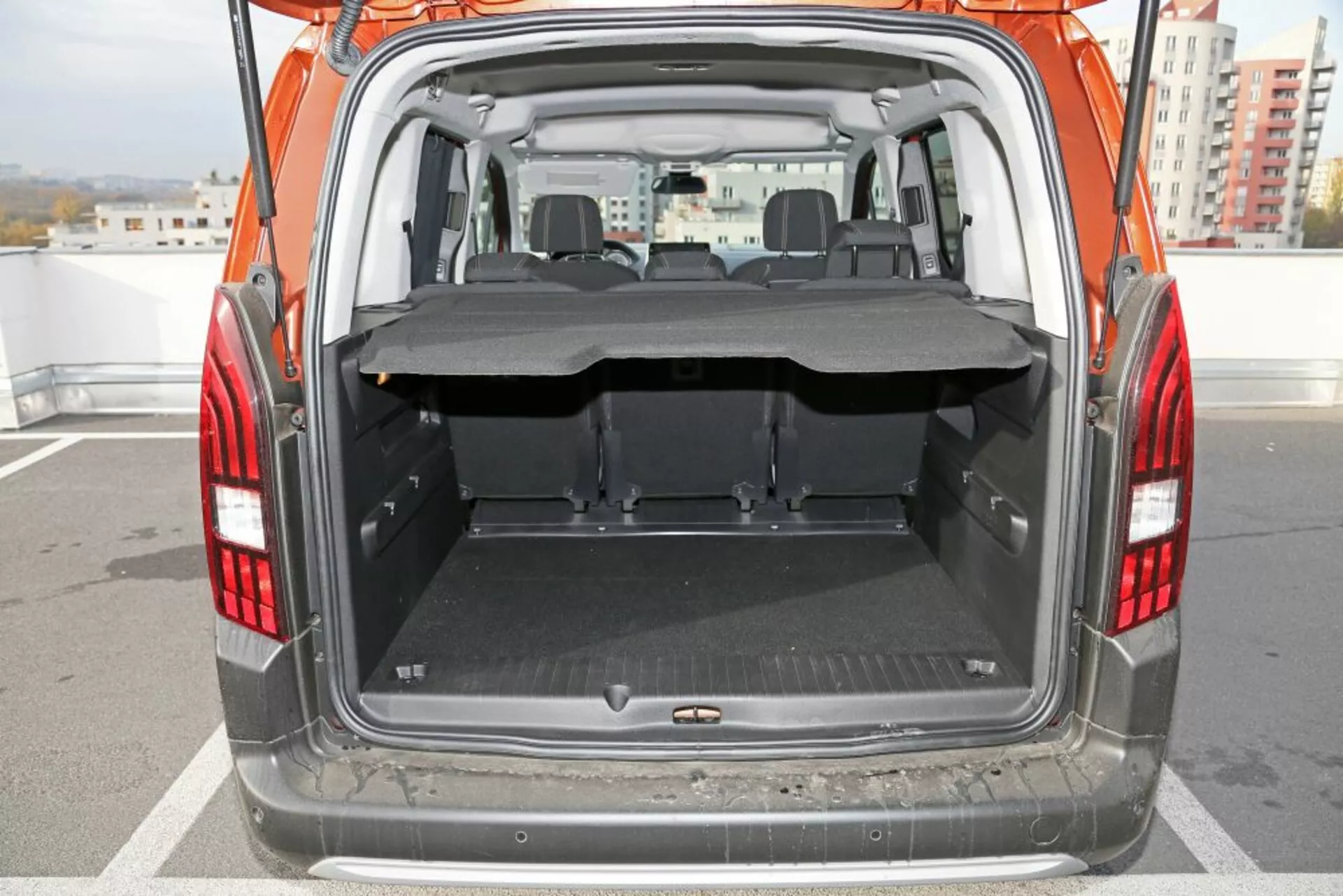 Priamy pohľad na otvorený kufor Peugeotu 3008 z roku 2016 ukazujúci priestranný nákladný priestor so sklopeným zadným sedadlom, ochrannou podložkou a čiastočne vysunutým nákladným krytom vo dne.