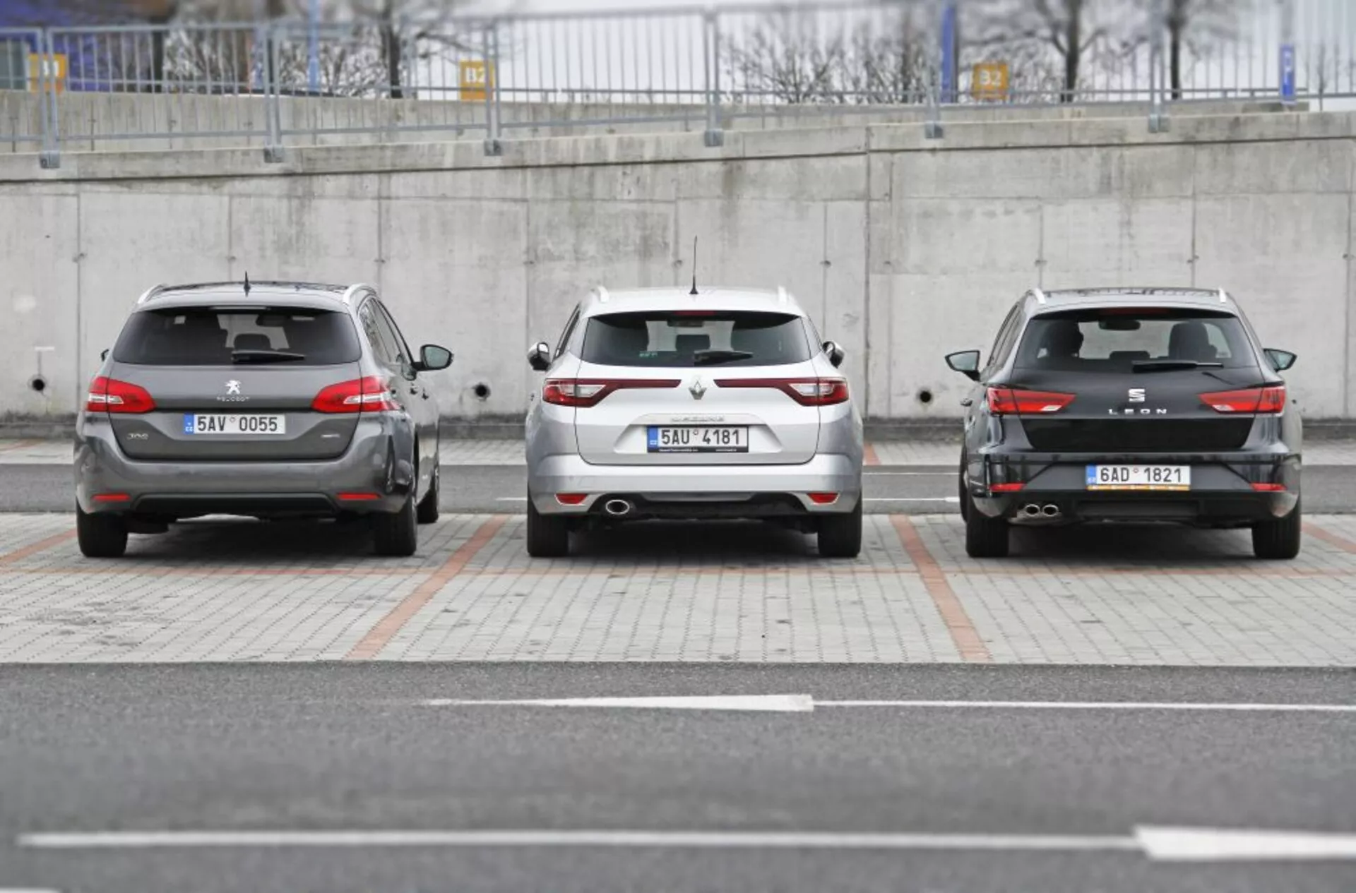 Tri vozidlá Peugeot 308 SW 2013 zaparkované vedľa seba s pohľadom na zadný dizajn vrátane zadných svetiel, nárazníkov a evidenčných čísel v mestskom parkovacom prostredí