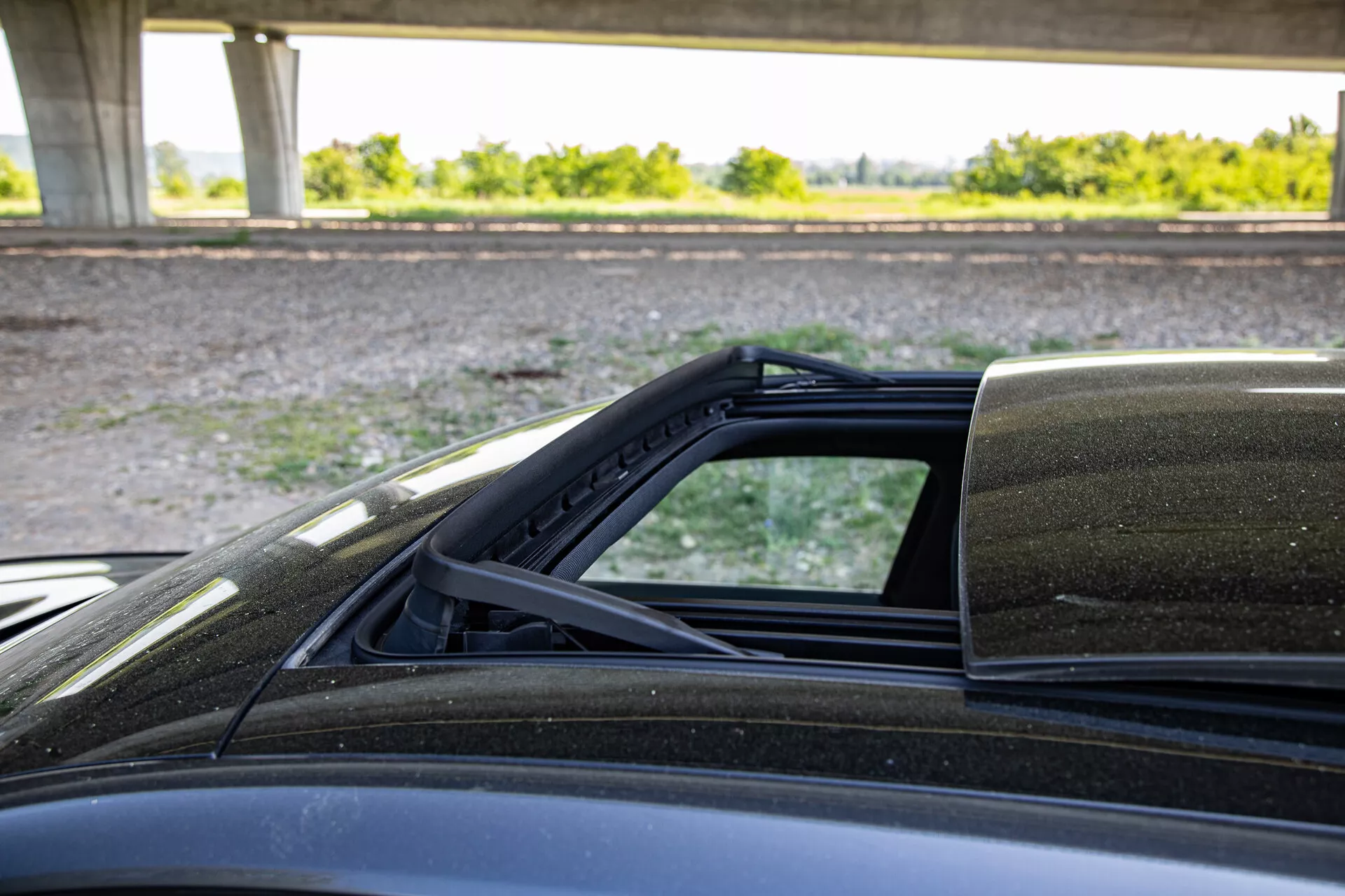 Detailný pohľad na mechanizmus sklápateľnej strechy Peugeot 408 2023 so zameraním na bodové spojenie s karosériou, záber zo strany spolujazdca zdôrazňuje vnútornú podšívku mäkké strechy, tesnenie proti poveternostným vplyvom a vonkajší lak.