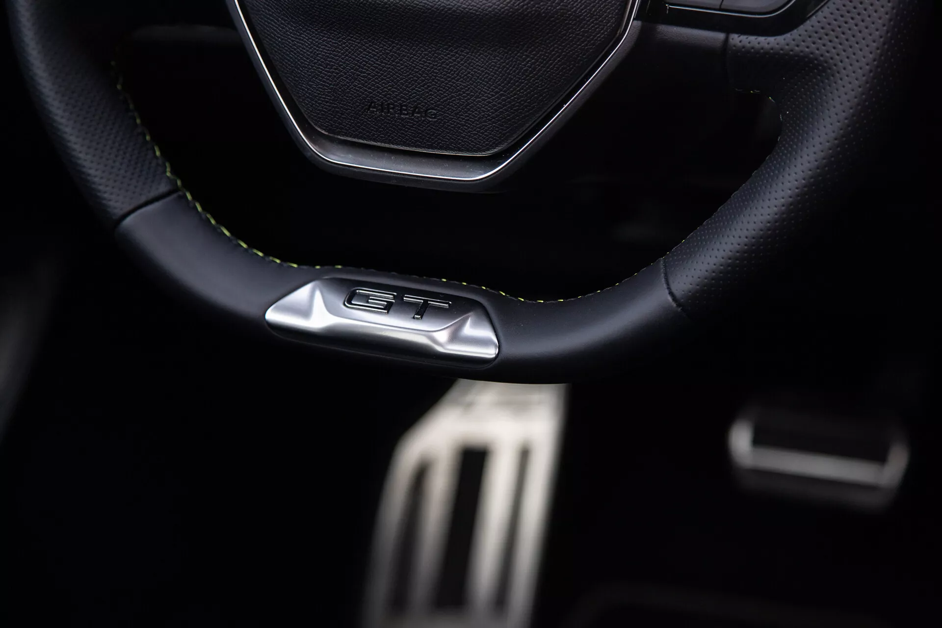 Interiér Peugeot 408 pre rok 2023 so zameraním na športový volant zošitý z kože alebo kože podobného materiálu s emblémom GT, kovové pedále pre výkon a prémiové prvky tmavého kokpitu