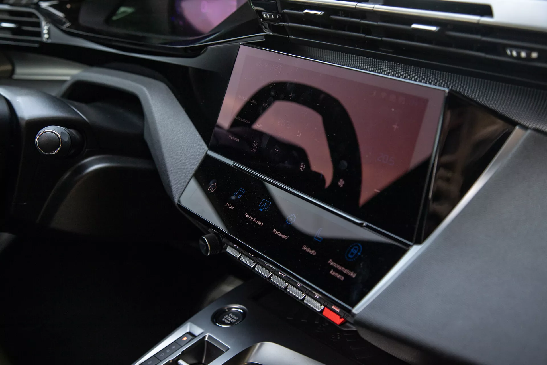 Interiér Peugeot 408 z roku 2023 ukazujúci stredovú konzolu a pokročilý informačno-zábavný systém s dotykovou obrazovkou, tlačidlá klimatizácie a elegantné dizajnové akcenty
