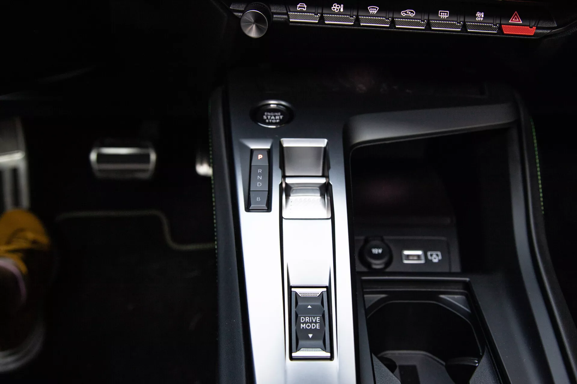 Detailný pohľad na stredovú konzolu Peugeot 408 2023 s radením v polohe Park, tlačidlom DRIVE MODE, elektronickou parkovacou brzdou a USB portmi, predvádzajúci moderný dizajn interiéru.