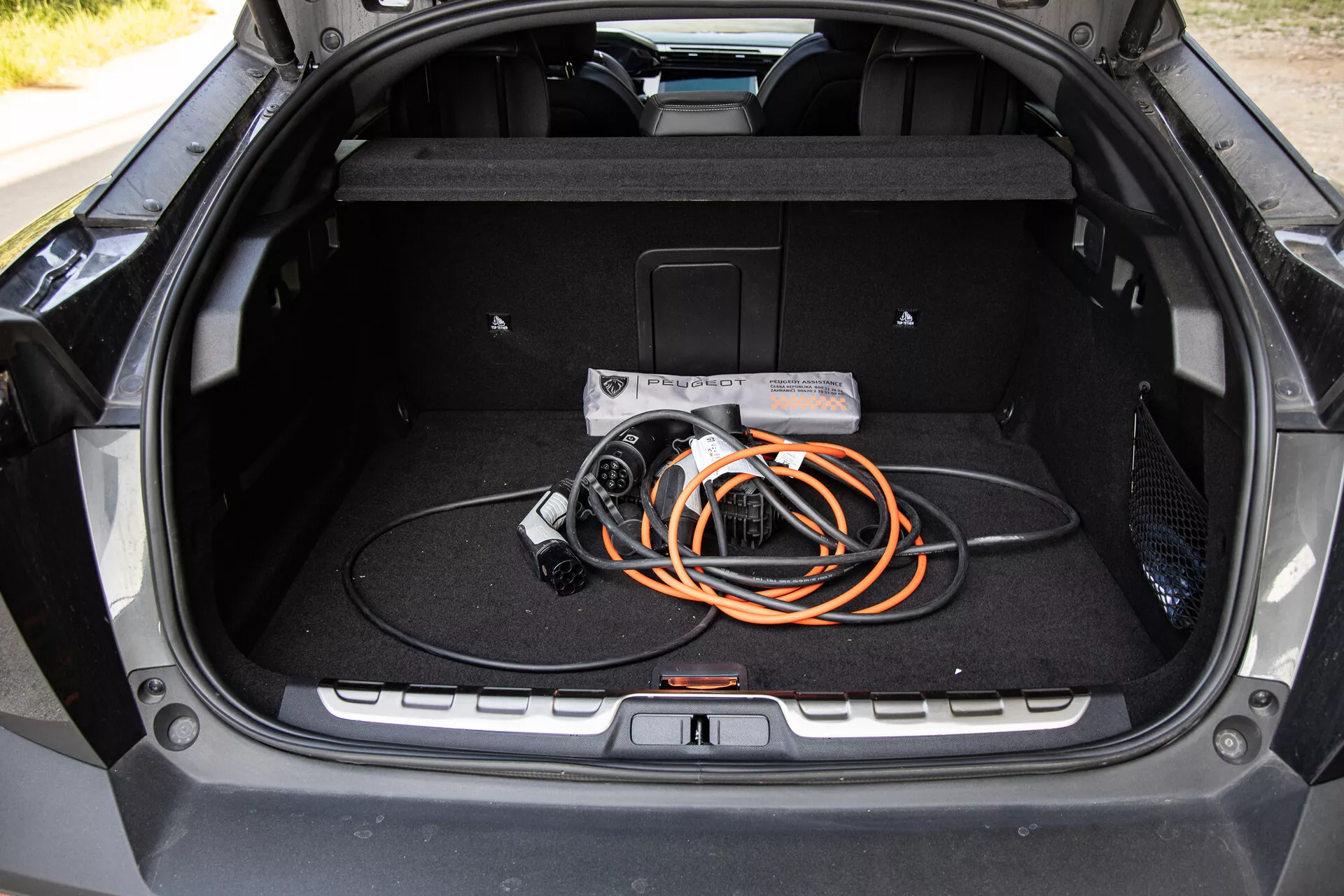 Interiér kufra Peugeot 408 2023 s prehľadom priestranného dizajnu a nabíjacím káblom pre elektrické vozidlá, zdôraznenie technológie EV a moderne kvality výroby.
