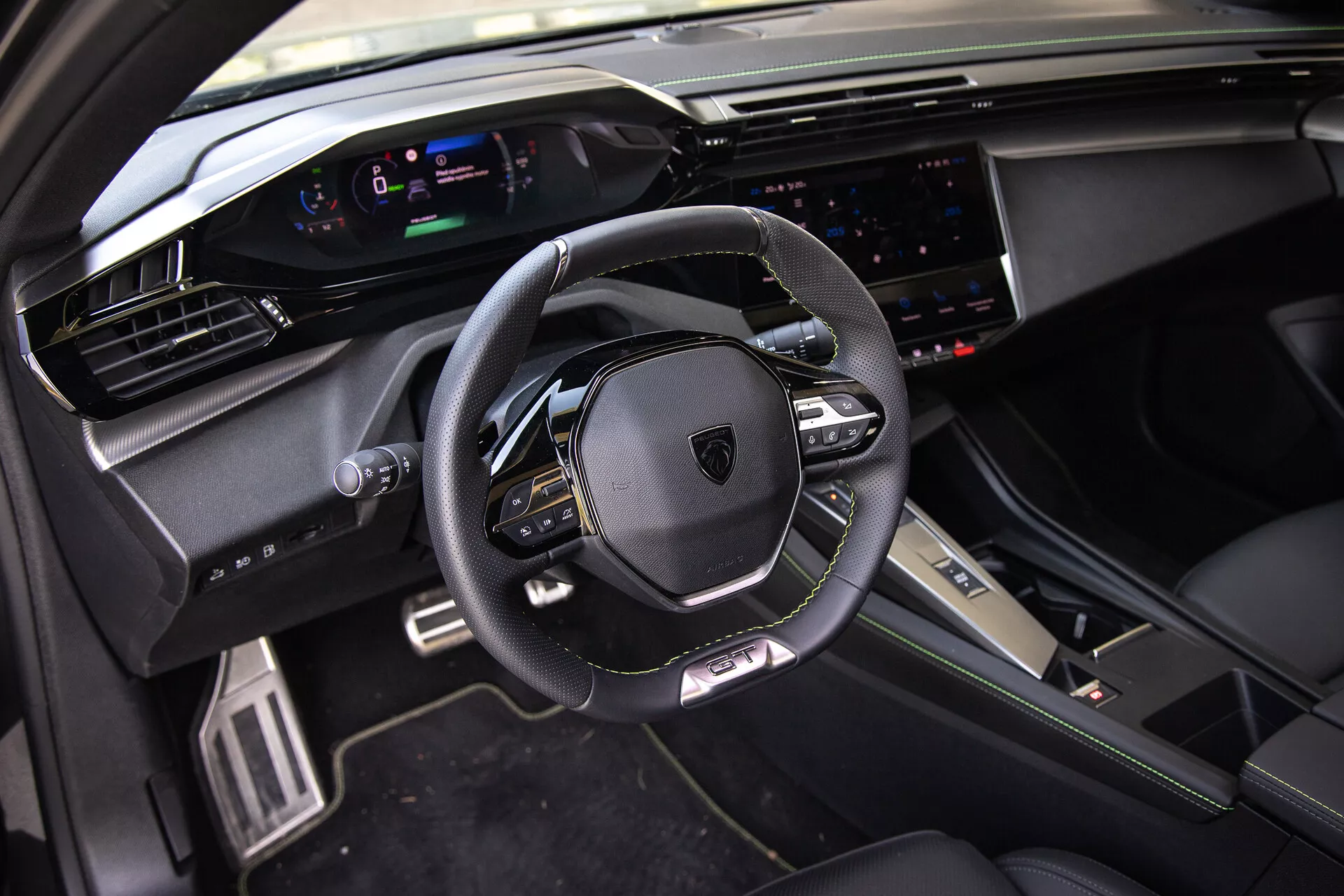 Interiér Peugeotu 408 z roku 2023 s koženým multifunkčným volantom, digitálnym prístrojovým panelom, širokým dotykovým infotainment systémom a športovo-prémiovými dizajnovými prvkami v prírodnom dennom svetle z pohľadu predného spolujazdca.