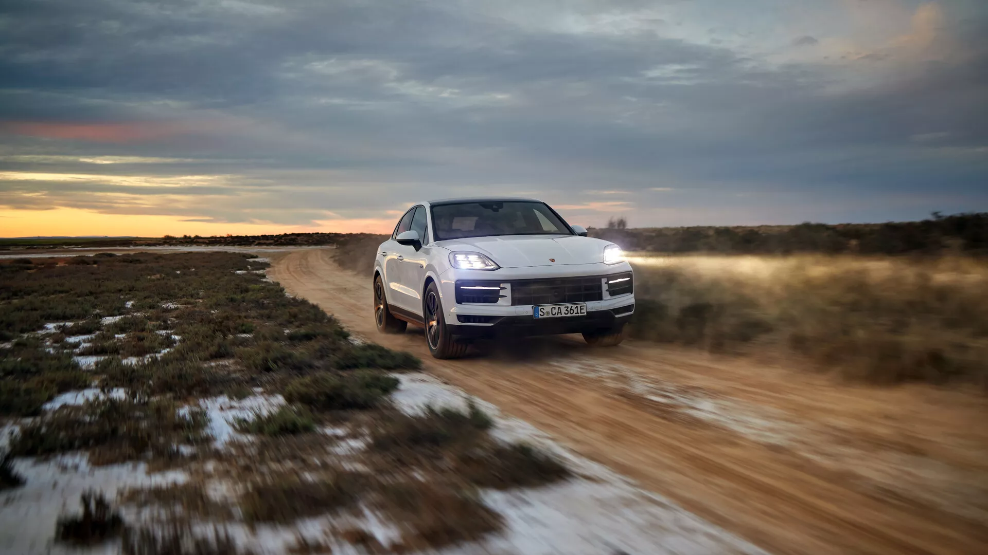 Model Porsche Cayenne 9YA Facelift z roku 2023 jazdiaci v teréne, ktorý ukazuje svoj trojštvrtinový predný pohľad s LED svetlometmi, aktívnym zavesením a systémom pohonu všetkých kolies pri súmraku
