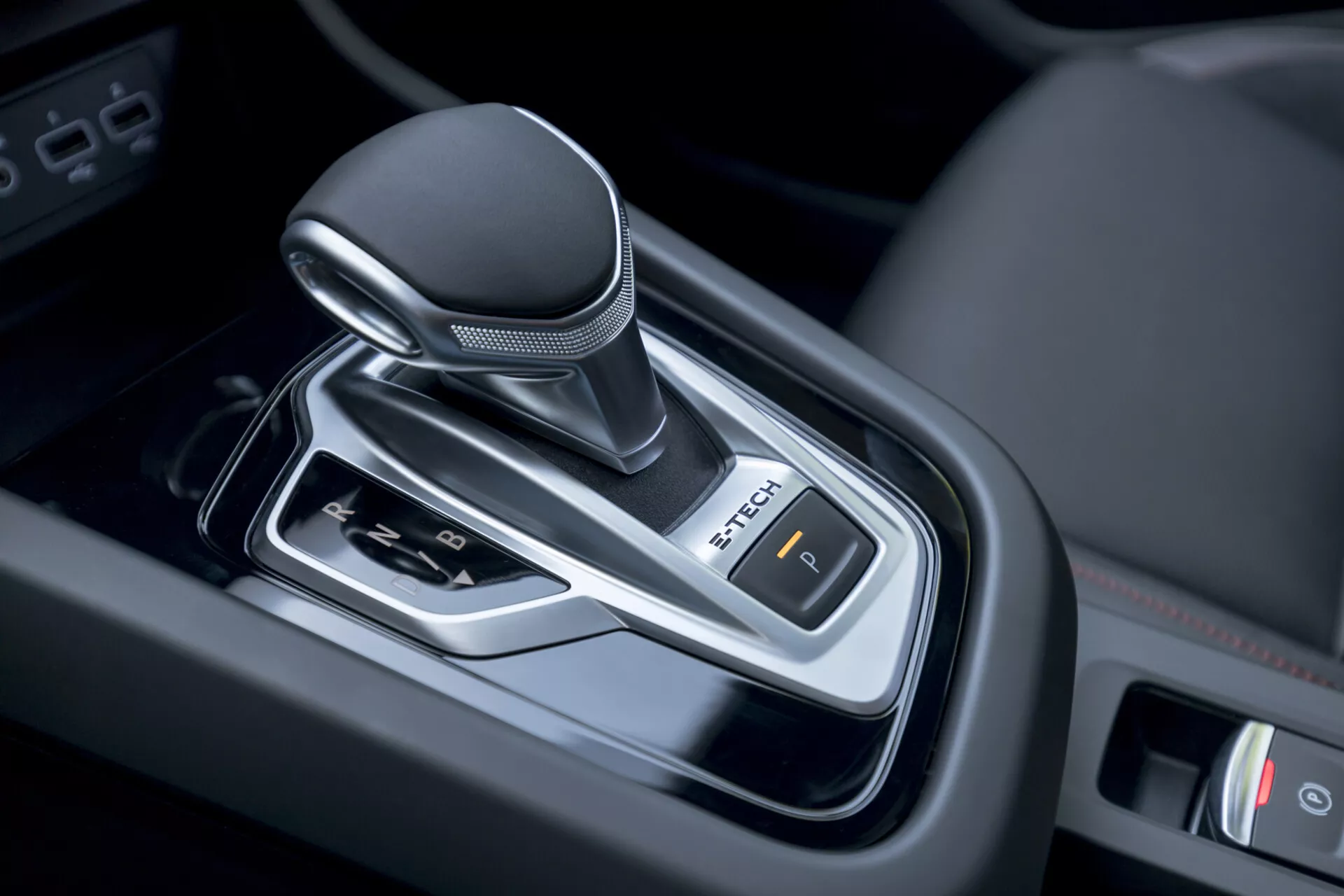Detailný pohľad na radiacu páku automatickej prevodovky Renault Arkana 2021 vo vnútri vozidla, predvádzajúci moderný dizajn s koženou rukoväťou, chrómovými akcentmi a ovládaním elektronickej parkovacej brzdy.
