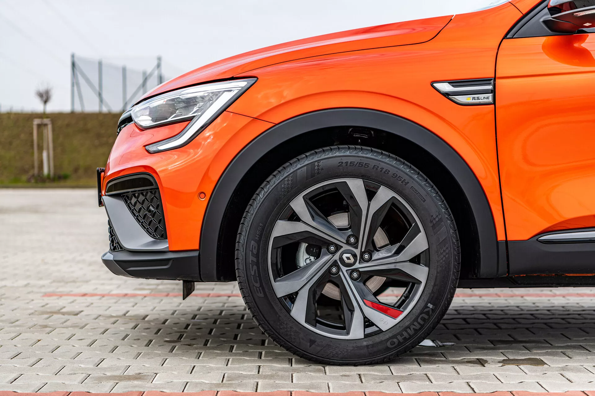 Detailný bočný pohľad na oranžovú Renault Arkana 2021 s viacramennými zliatinovými kolesami, nízkoprofilovými pneumatikami, brzdovým systémom vyššieho výkonu a LED denným svietením