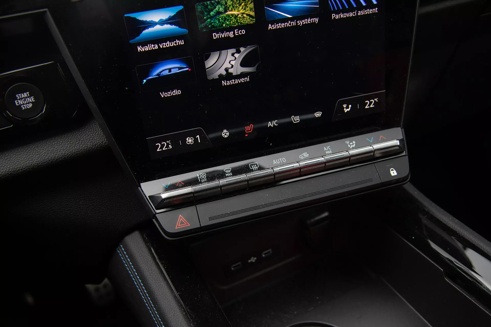 Detailný pohľad na interiér Renault Austral 2022 s centrálnou konzolou a dotykovým infotainment displejom zobrazujúcim možnosti Kvalita vzduchu, Eco Driving, Asistentné systémy a Parkovací asistent, ovládanie klimatizácie a tlačidlo pre núdzové situácie.