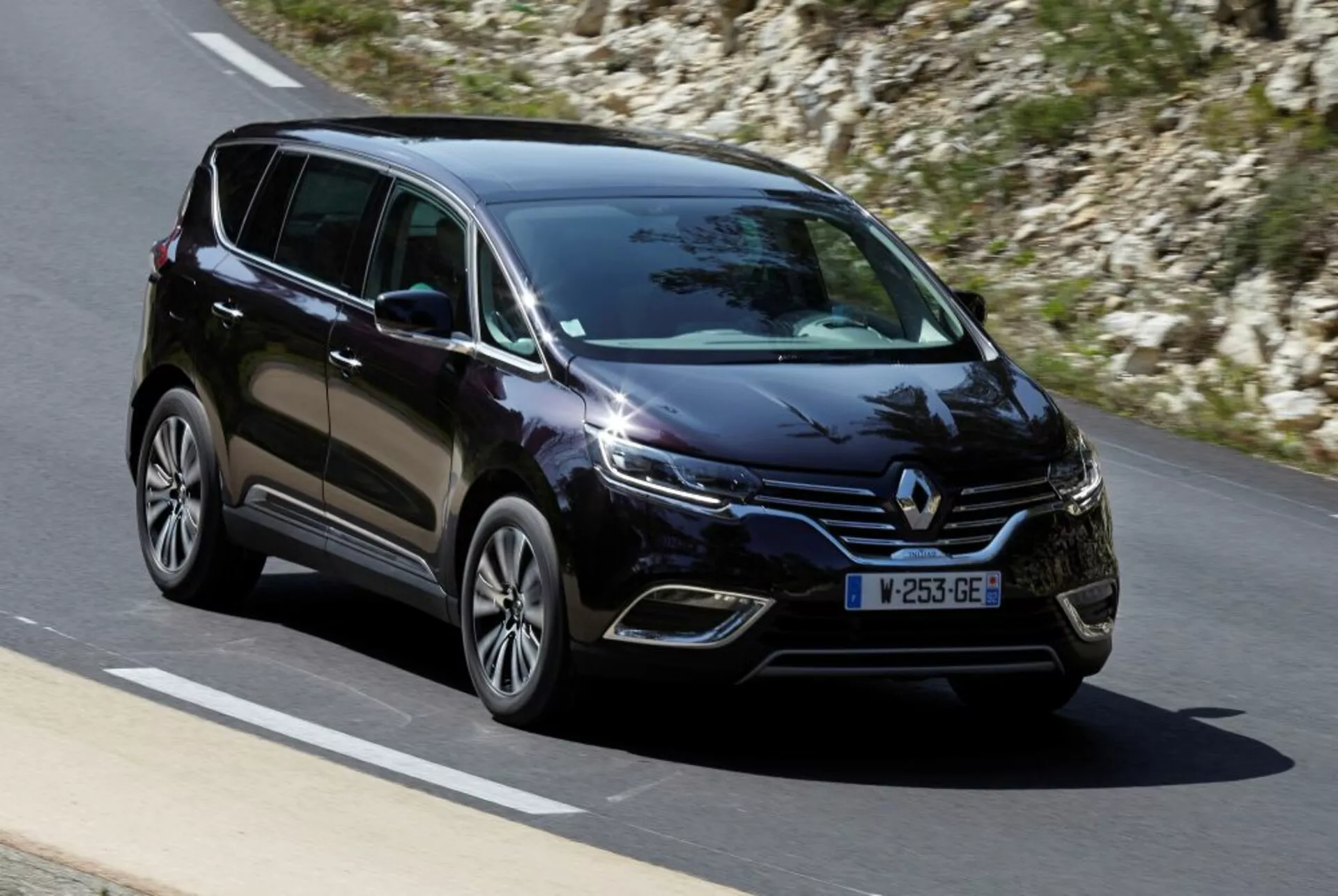 Minivan Renault Espace 2015 v pohybe na spevnenej ceste, pohľad z prednej časti a zo strany ukazuje LED svetlomety, zliatinové kolesá a moderné dizajnové prvky