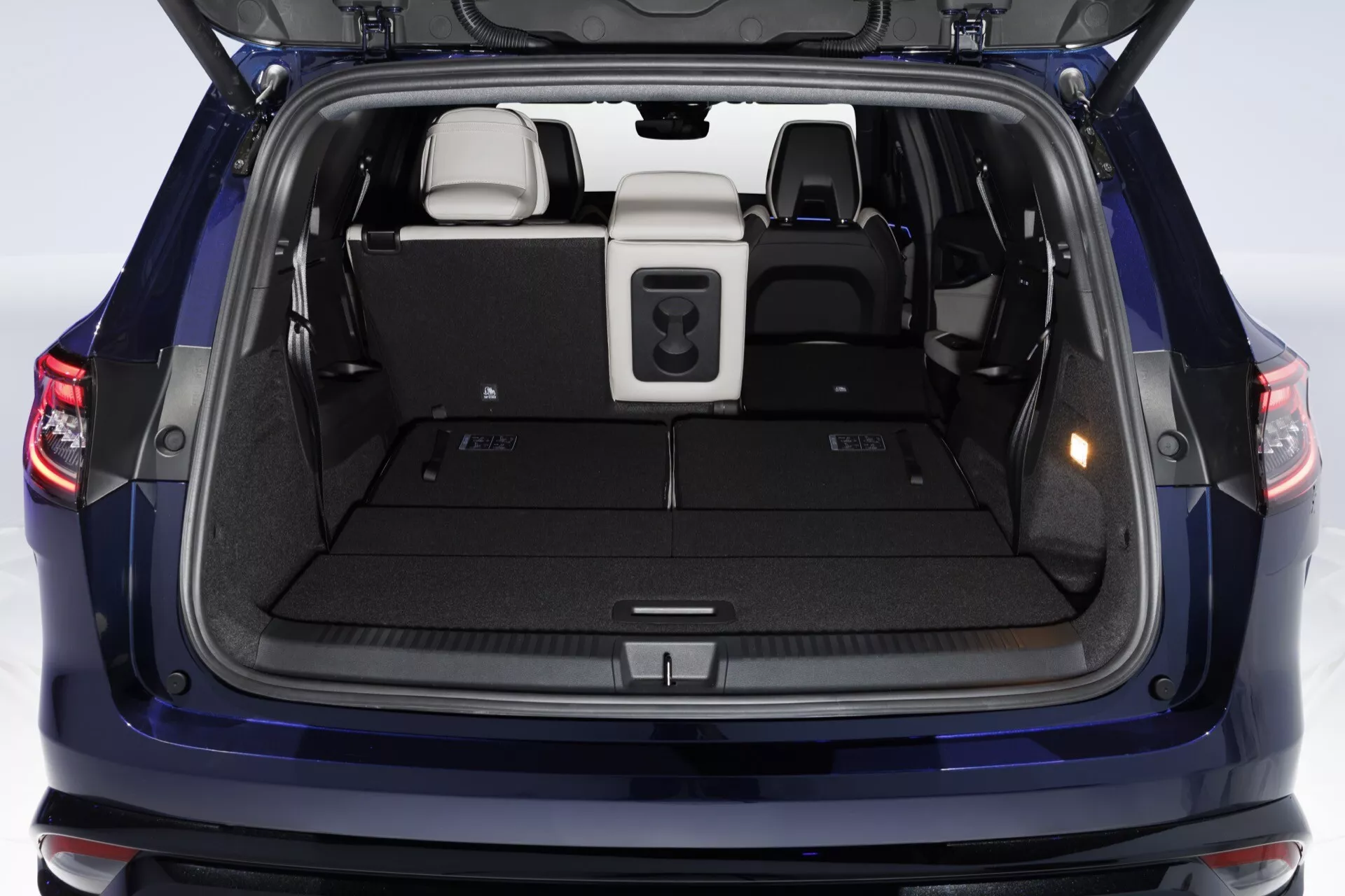 Zadný nákladový priestor Renault Espace 2023 s otvoreným dverami batožinového priestoru, zadnými sedadlami deliteľnými v pomere 60/40, zasúvateľným krytom nákladového priestoru, ergonomickými ťahacími rukoväťami a kobercom v neutrálnych tónoch
