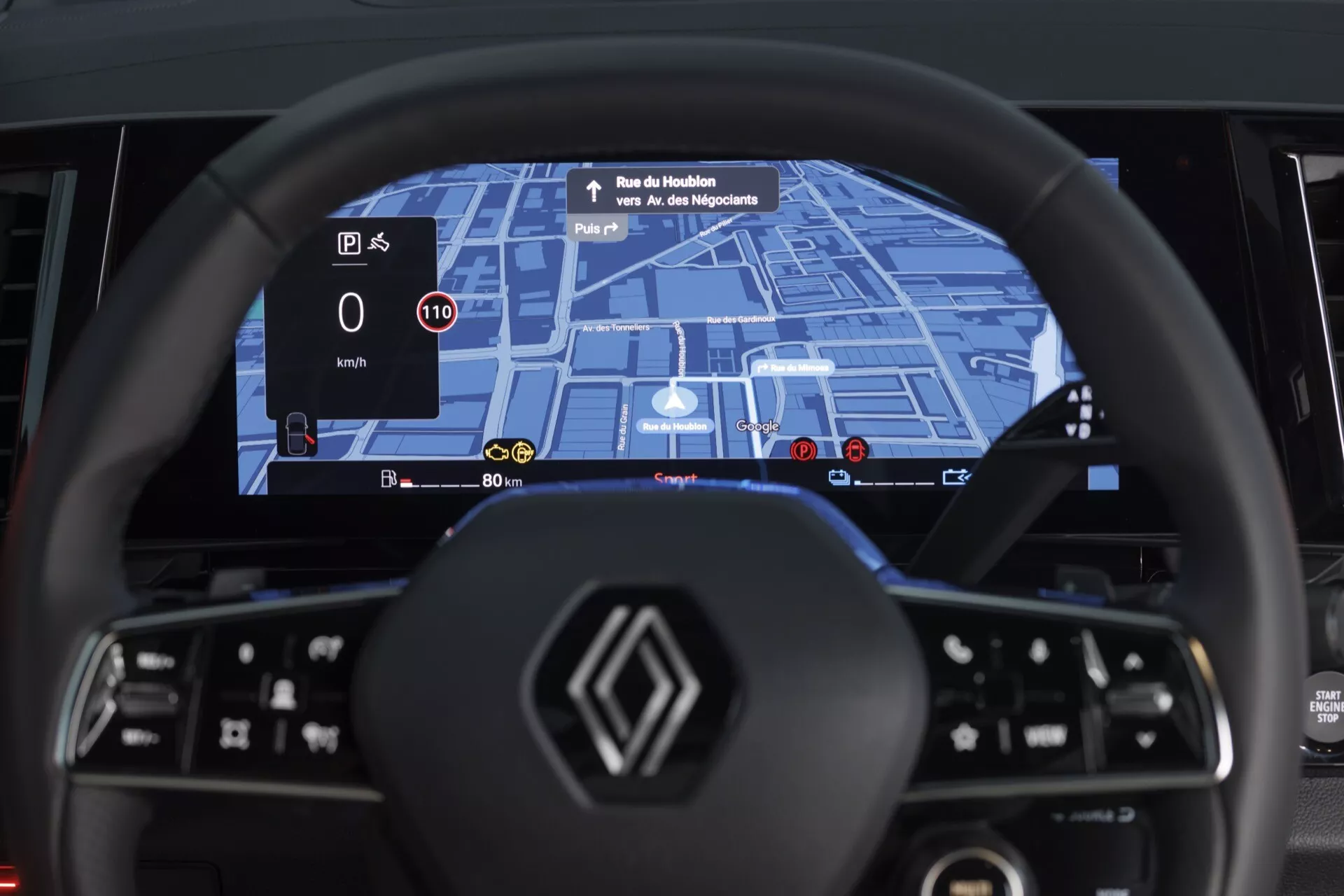 Interiér Renault Espace VI 2023 z pohľadu vodiča, ktorý zdôrazňuje moderný volant s plochým dnom s multifunkčnými ovládacími prvkami a širokouhlý digitálny prístrojový panel s vstavanou navigáciou GPS, detekciou rýchlostných obmedzení a displejom úrovne energie pre hybridný alebo elektrický pohon, plus HUD projekciu rýchlosti a navigačných pokynov