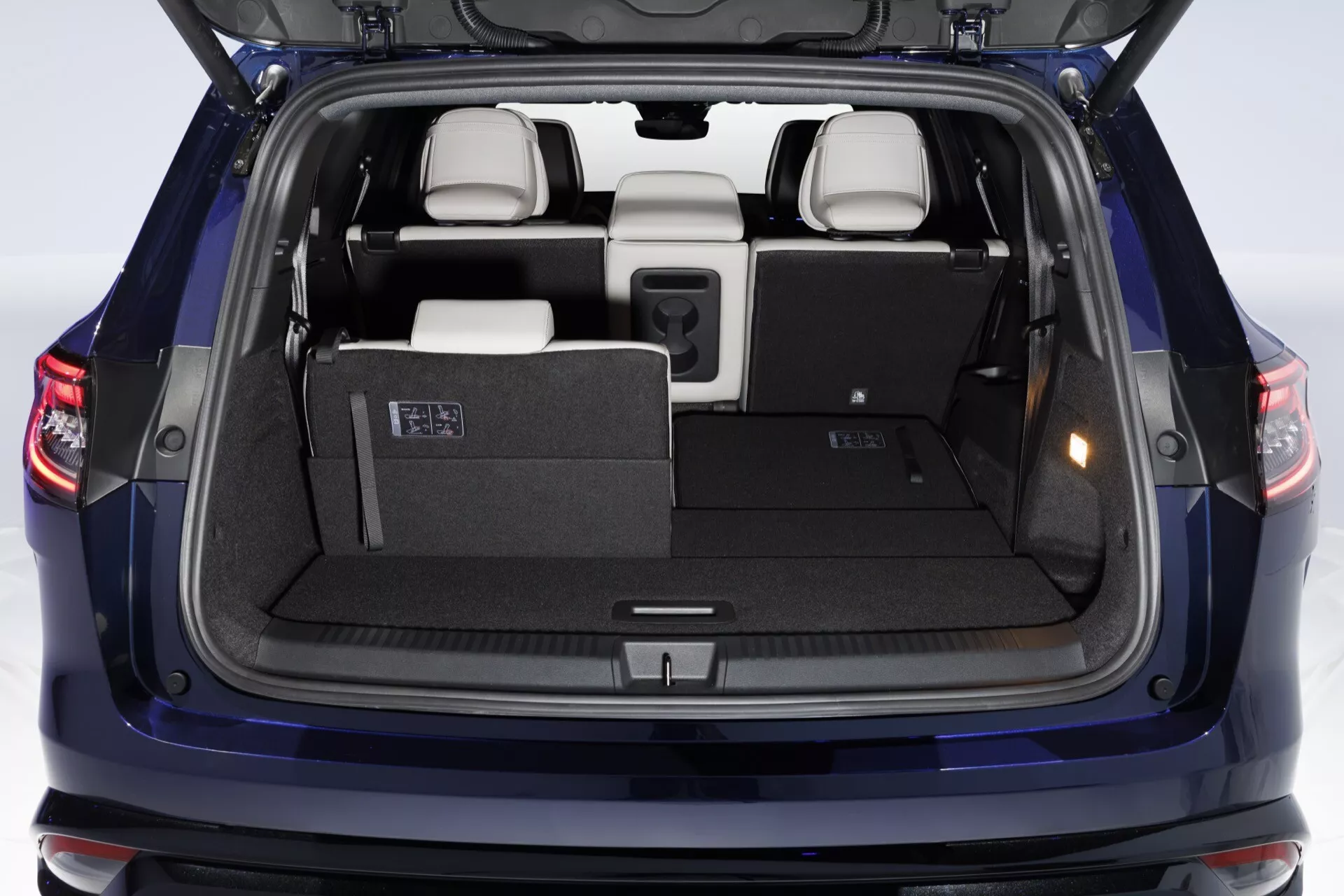 Renault Espace VI 2023 zobrazujúci zadný pohľad s otvoreným nákladným priestorom, zdôrazňujúci priestranný kufor, LED zadné svetlá, sklopné sedadlá tretej rady, materiály vysokokvalitného interiéru, užívateľsky prívetivé páky pre konfiguráciu sedadiel, kryt súkromia, detailné čalúnenie zadných dverí a parkovacie senzory