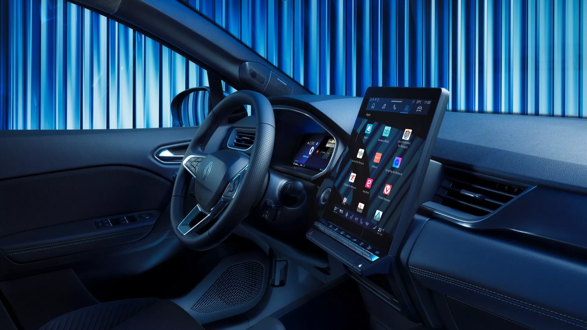 Obrázok zobrazuje interiér Renault Symbioz 2024 (1. generácia), ktorý sa vyznačuje moderným a sofistikovaným dizajnom. Snímka je urobená z mierne posunutého uhla smerom k prednému sedadlu spolujazdca, čím poskytuje jasný pohľad na vodičskú zónu. Vo popredí je výrazný volant so striebornými prvkami a ovládacími tlačidlami. Za volantom je vidieť digitálnu prístrojovú dosku s farebným displejom. Stredná časť prístrojovej dosky dominuje veľký, vertikálne orientovaný dotykový infotainment systém. Interiér má dvojfarebný dizajn s vysoko kvalitnými materiálmi, úzkym ventilačným otvorom pod obrazovkou a ovládacími panelmi na dverách vodiča.