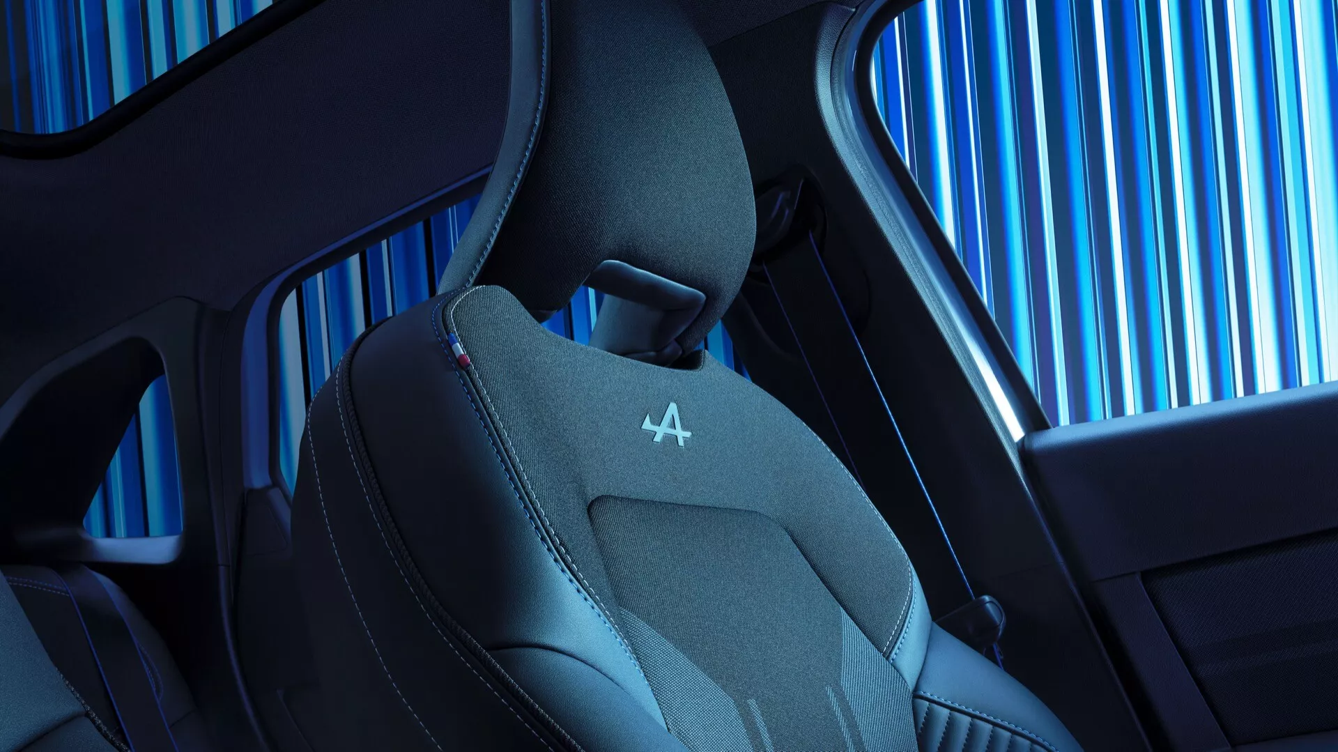 Detailný pohľad na interiér sedadla vozidla Renault Symbioz 2024 prvej generácie, zdôrazňujúci moderný dizajn a technologické funkcie. Zobrazuje hornú časť sedadla s ergonomickým tvarom, tvarovanými bočnými opierkami a kombináciou kože a priedušnej látky pre luxus a pohodlie. Výrazné červené prešívanie na opierke hlavy s reliéfnym logom spolu s náhľadom na vzor bočného okna vozidla a elegantný dizajn kabíny.