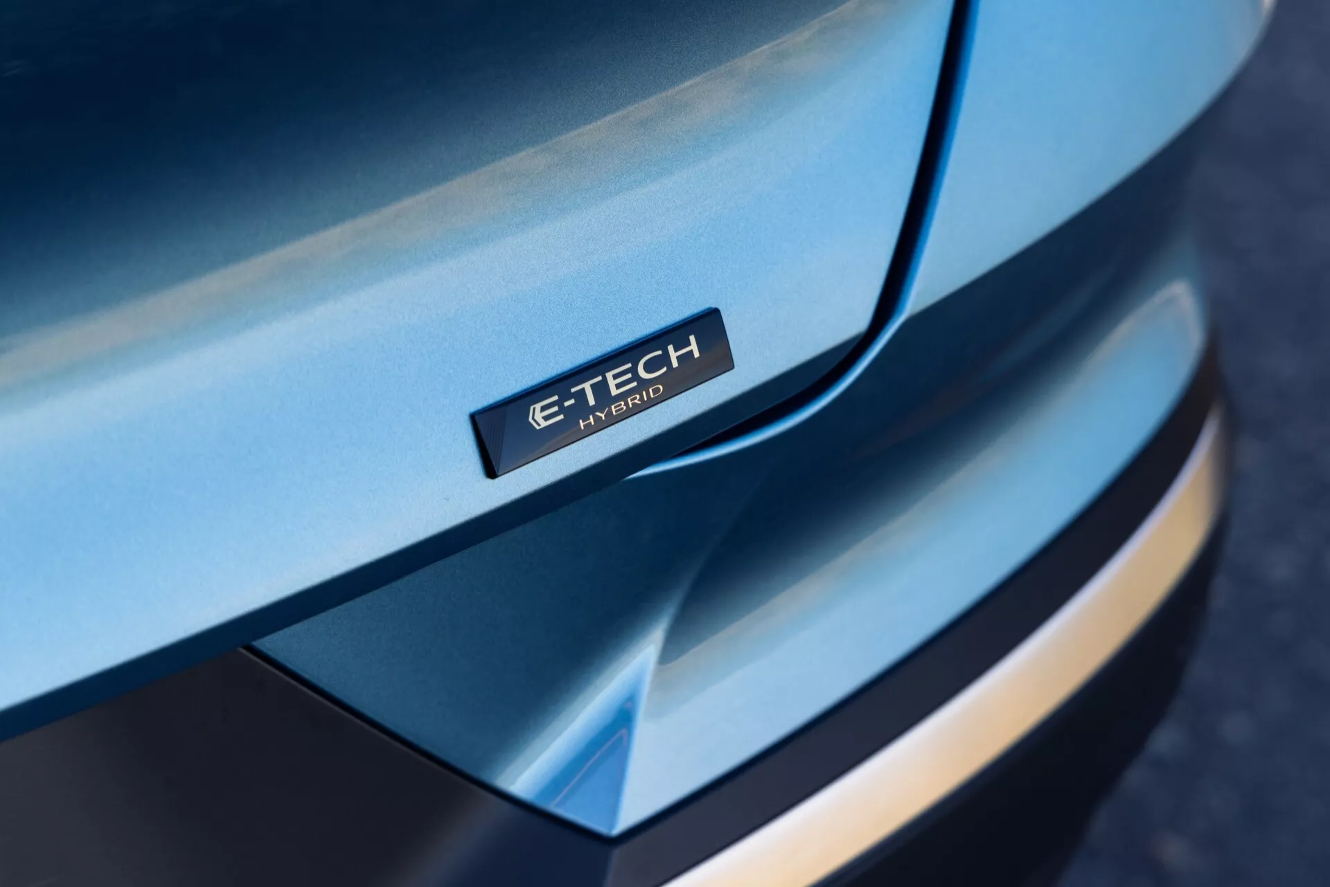Kozubný šikmý pohľad na prednú časť Renault Symbioz 2024, zameriavajúci sa na elegantnú, zakrivenú kapotu s odznakom 'E-TECH Hybrid', viacvrstvový dizajn predného nárazníka, kontrastné farby a prémiový vzhľad, zdôrazňujúci hybridnú technológiu.