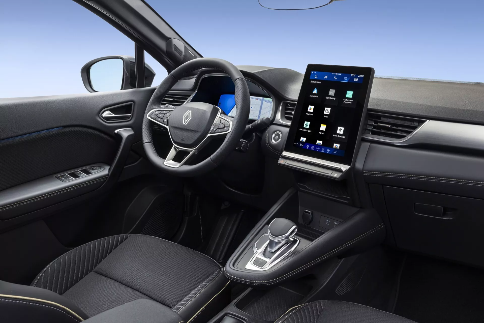 Záber interiéru Renault Symbioz 2024, prvej generácie, zdôrazňujúci modernú prednú kabínu z pohľadu pravého zadného pasažiera. Funkcie zahŕňajú multifunkčný volant potiahnutý kožou, zvisle orientovaný dotykový informačno-zábavný systém zobrazujúci multimediálne rozhrania a zjednodušenú stredovú konzolu s radiacou pákou a voličom jazdných režimov, ilustrujúce pokročilé možnosti pripojenia a kontroly asistenta vodiča.