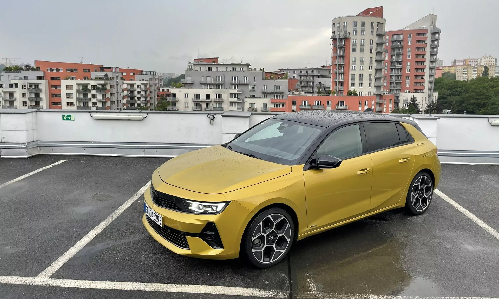 Hatchback Seat Arona 2017 v výraznej žltej farbe s kontrastnou čiernou strechou, zaparkovaný v viacpodlažnej štruktúre, predvádza štíhle LED svetlomety, výraznú mriežku s pokročilými senzormi, športové viaceramenné zliatinové kolesá a tónované okná v zamračených, daždivých podmienkach