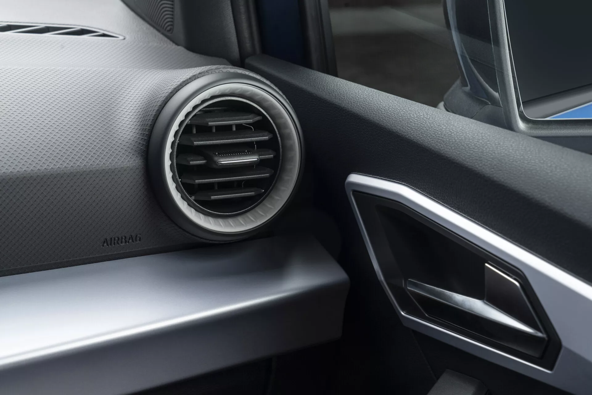 Interiérový pohľad na Seat Arona 2017 sústredený na prístrojovú dosku na strane spolujazdca s kruhovou klimatizačnou mriežkou, striebornými akcentmi a náhľadom na infotainment systém