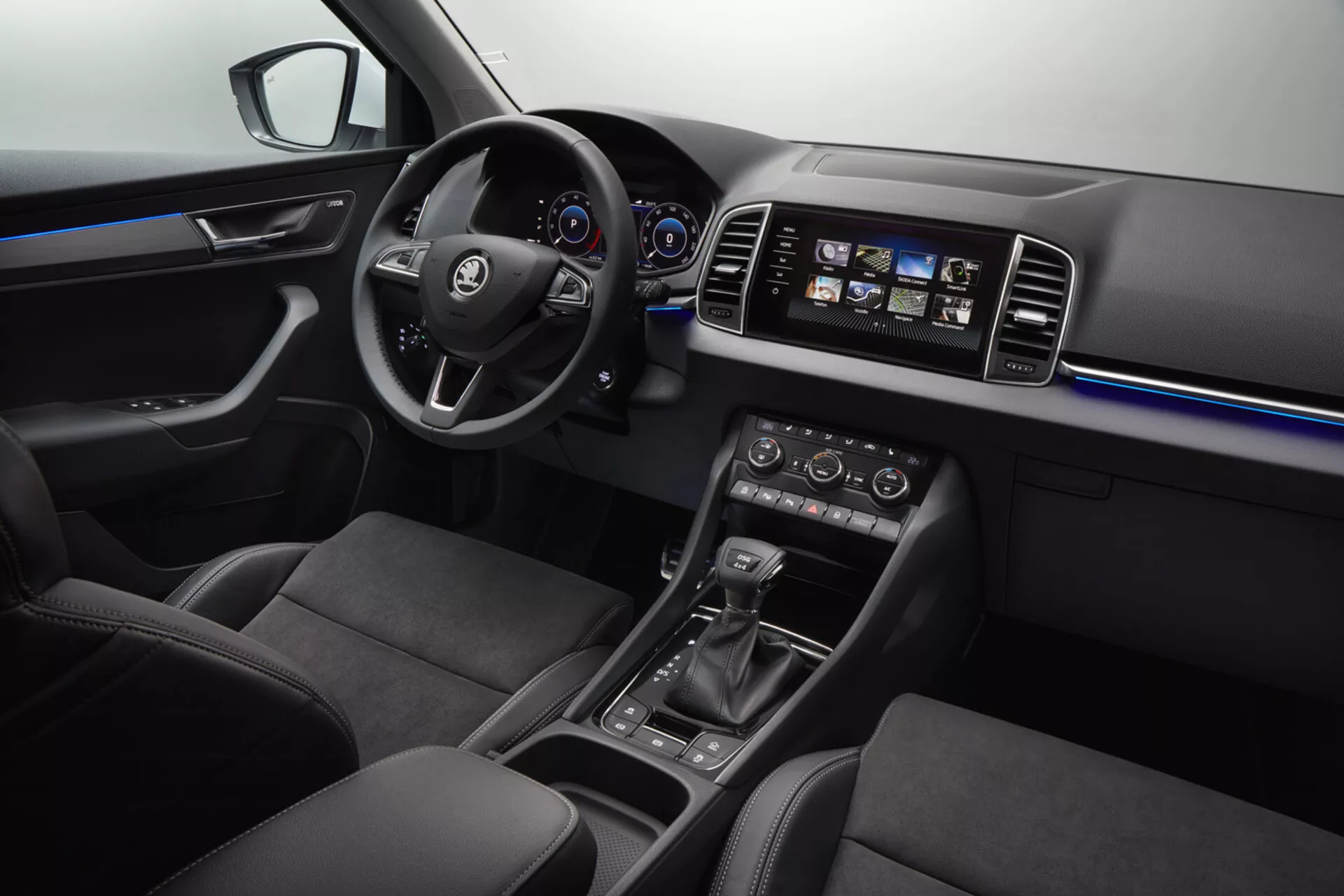 Interiér Škoda Karoq 2017 s multifunkčným koženým volantom s logom, digitálnym prístrojovým panelom, dotykovým informačným systémom, klimatizáciou s dvomi zónami, automatickou voličkou rýchlostí, ambientným osvetlením, ergonomickými koženými sedadlami a ovládaním elektrických okien.