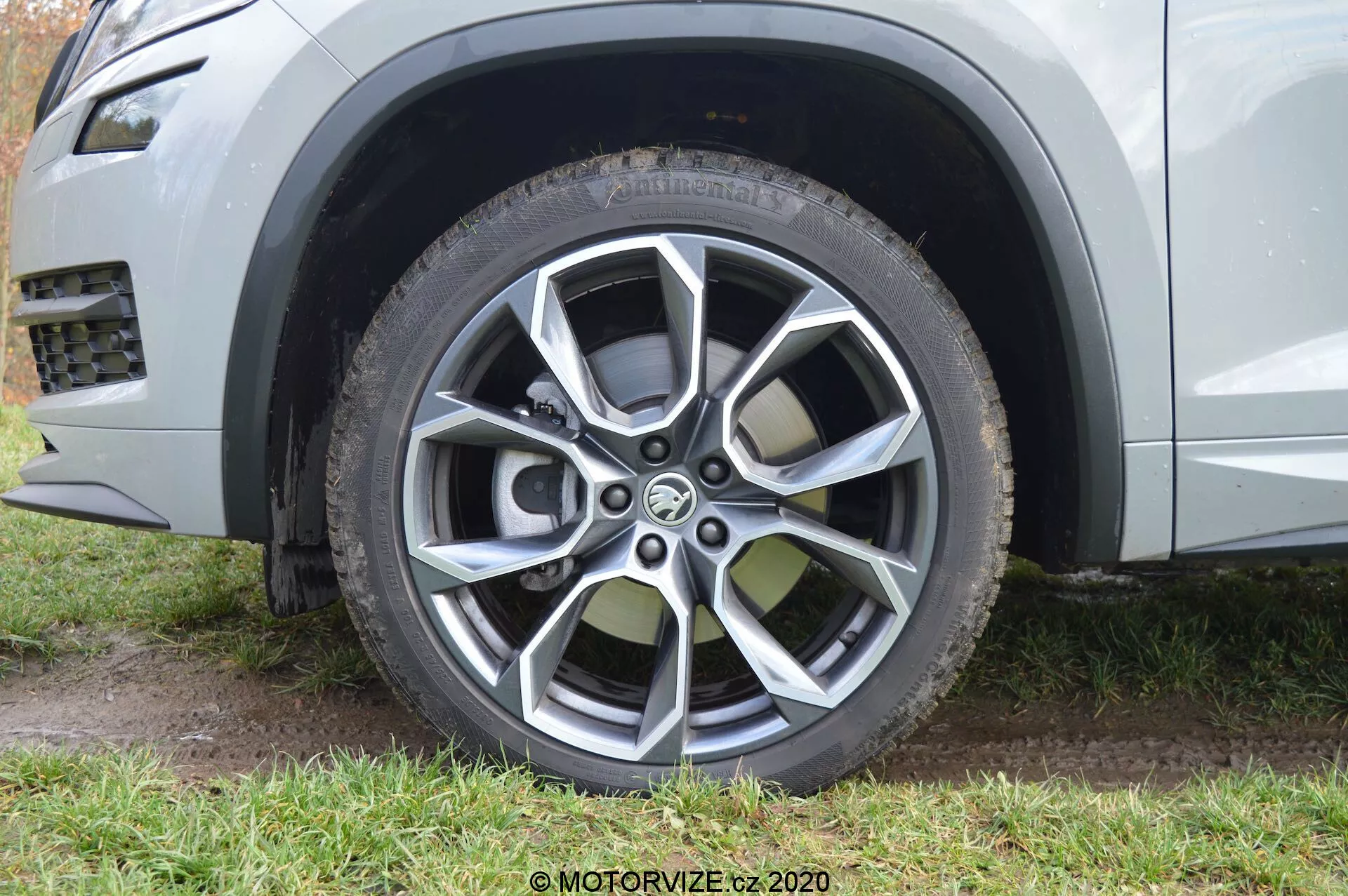 Detailný pohľad na predné koleso na strane spolujazdca na modeli Skoda Kodiaq 2017, ukazujúci moderný dizajn viaclúčového zliatinového ráfu s lakovanými a mechanicky opracovanými povrchovými úpravami. Zliatinový ráfik má desať lúčov s vysokým kontrastom medzi tmavosivými a svetlými kovovými farbami, určený na estetický vzhľad a ochranu pred poškodením obrubníkom. Obrázok tiež zvýrazňuje celoročnú alebo terénnu pneumatiku s viditeľným dezénom a dizajnom chrániča ráfu, a čiastočne zobrazuje svetlometalickú striebornú alebo sivú farbu karosérie spolu s plastovým lemom okolo oblúka kolesa, čo naznačuje robustnú a terénnu estetiku SUV.