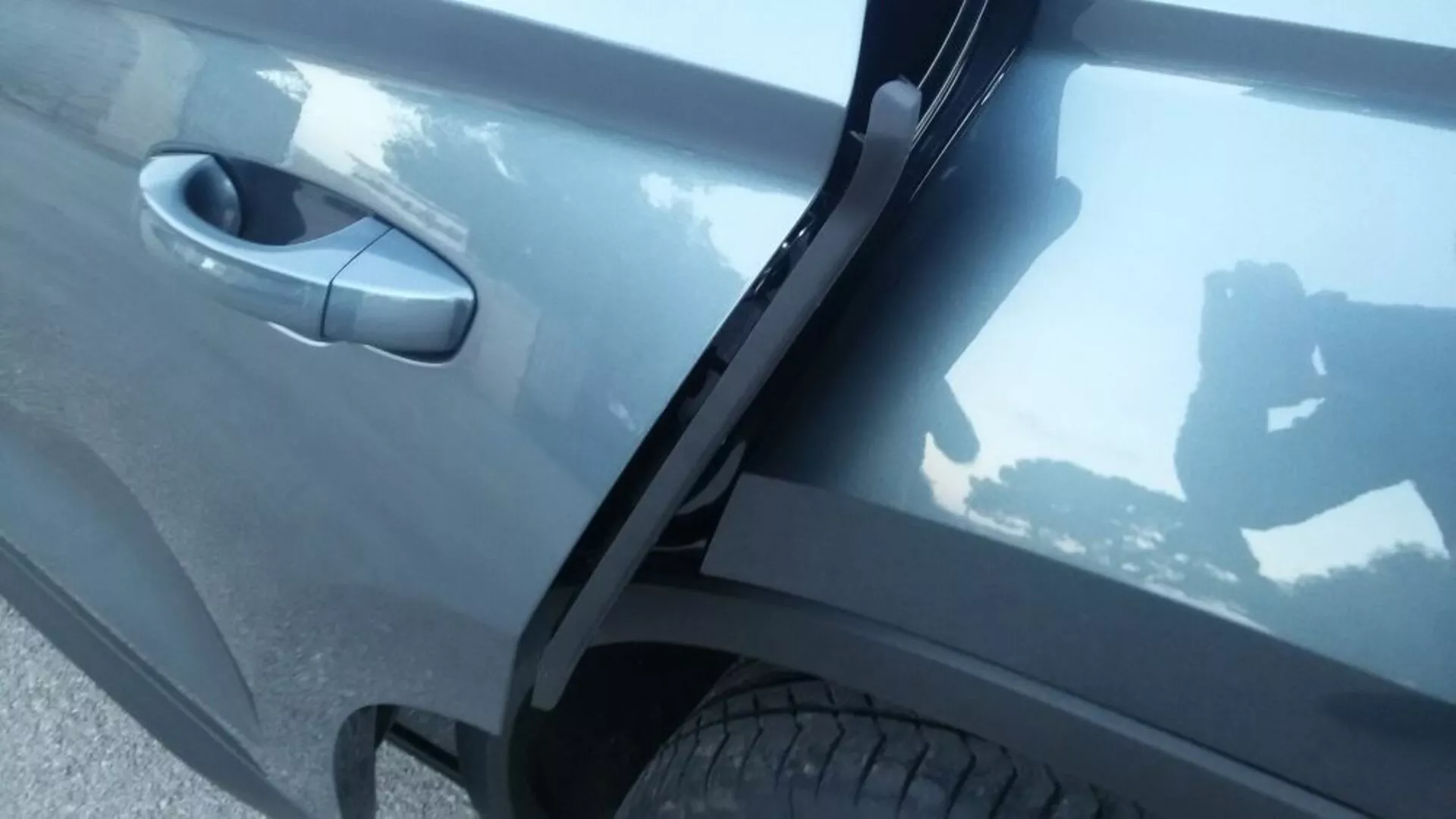 Detailný bočný pohľad na Škoda Kodiaq 2017 zameraný na oblasť predných pravých dverí s detailmi zdôrazňujúcimi tmavošedú reflexnú farbu auta, moderný dizajn kľučky dverí a integrovaný prah pod difúznym vonkajším osvetlením.