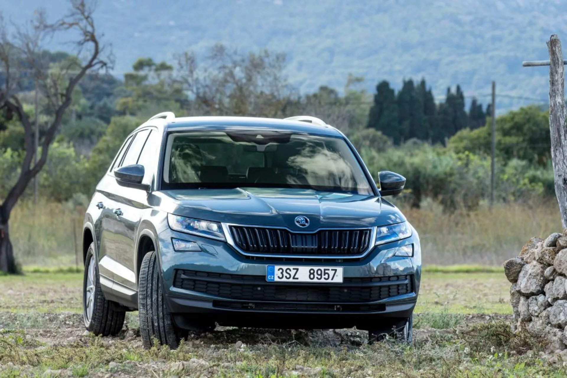 Skoda Kodiaq z roku 2017 v dynamickom zobrazení z predného a bočného uhla ukazuje LED svetlomety, denné svietenie, prednú mriežku s vertikálnymi lamelami, disky z ľahkých zliatin s viacerými špicami, ochranné lemy a kryty karosérie, zrkadlá so smerovkami a tónované okná, v prírodnom prostredí vhodnom pre jazdu v teréne