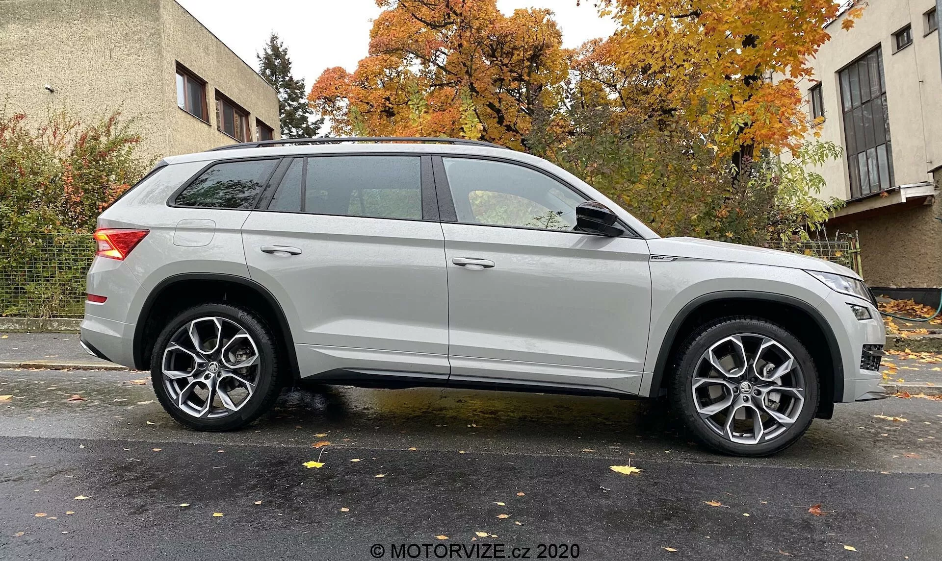 Bočný profil strieborného SUV Skoda Kodiaq 2017 zachytený z mierneho uhla, zvýrazňujúci predné koleso a blatník. Ukazuje dĺžku vozidla a dizajnové prvky, ako sú moderné svetlomety, viacramenné zliatinové kolesá, výrazná charakterová línia, strešné nosiče a elegantné zadné svetlá. Neutrálne pozadie s rovnomerným osvetlením. Foto: MOTORVIZE.cz 2020.