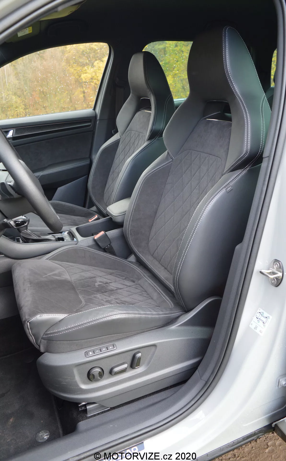 Interiérový pohľad na Škoda Kodiaq 2017 zameraný na vodičove sedadlo a okolitú oblasť, s čalúnením z čiernej kože s diamantovým prešívaním, integrovanou opierkou hlavy, bočným podperovaním pre dynamické riadenie a elektronickým nastavením sedadiel s ovládacími tlačidlami. Viditeľné črty obsahujú spodný rám dverí s prahovou lištou a reproduktorovú jednotku, čo naznačuje luxusný a športový interiér s pokročilou technológiou sedadiel.
