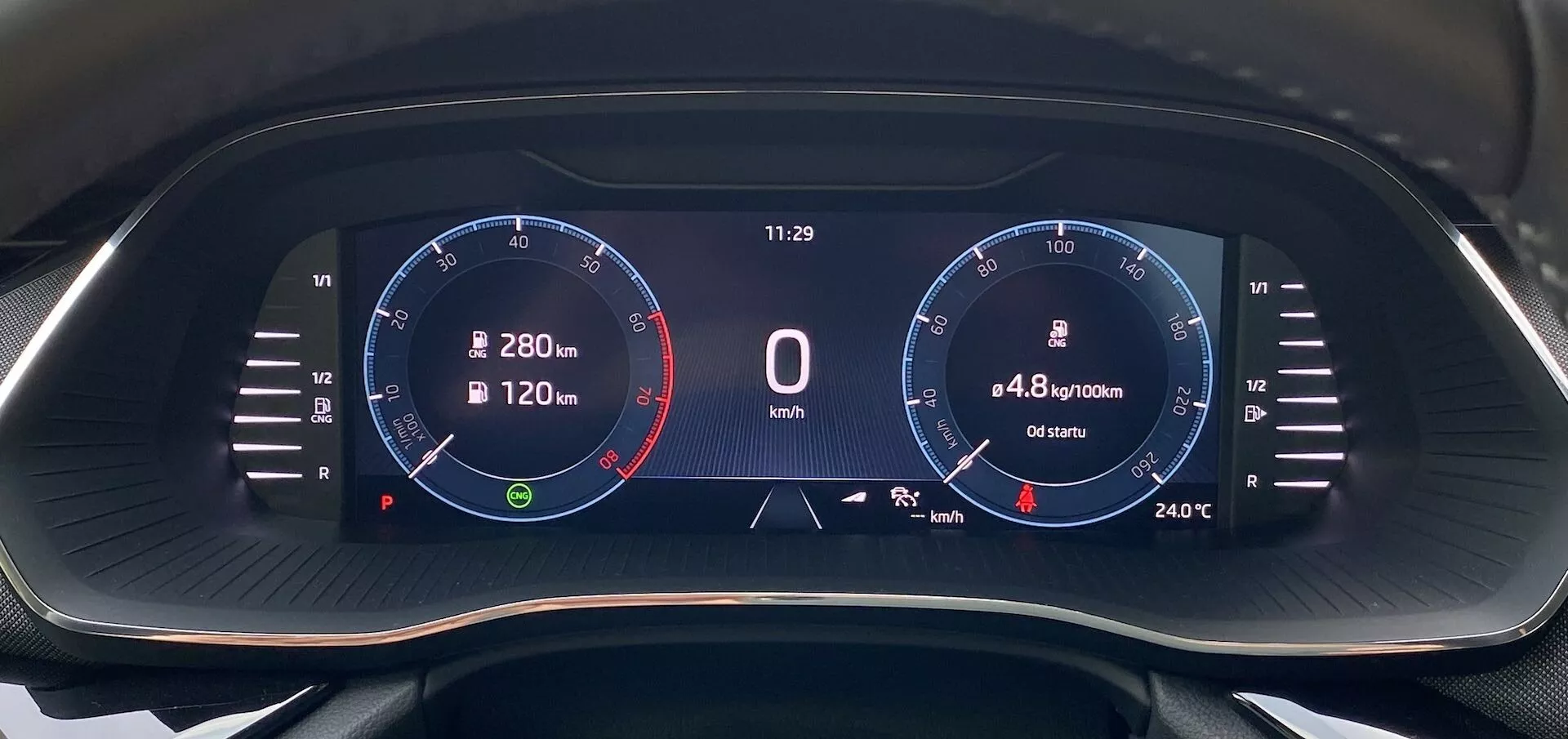 Detailný pohľad na digitálny prístrojový panel Škoda Octavia 2020 z pohľadu vodiča, s širokouhlým displejom s čiernym pozadím a jasnou digitálnou grafikou. Na ľavej strane je otáčkomer až do 8 000 ot./min s červeným označením od 6 500 ot./min, ručička v pokoji. V strede sa zobrazuje rýchlosť '0 km/h', hodiny '11:29', spotreba paliva '4,8 l/100 km' a vzdialenosť '6540 km'. Na pravej strane je grafikón podobný rýchlomeru s číslami až do 280 km/h a teplota '24°C'. Ikony zahŕňajú navigačný kompas a ukazovateľ stavu paliva.