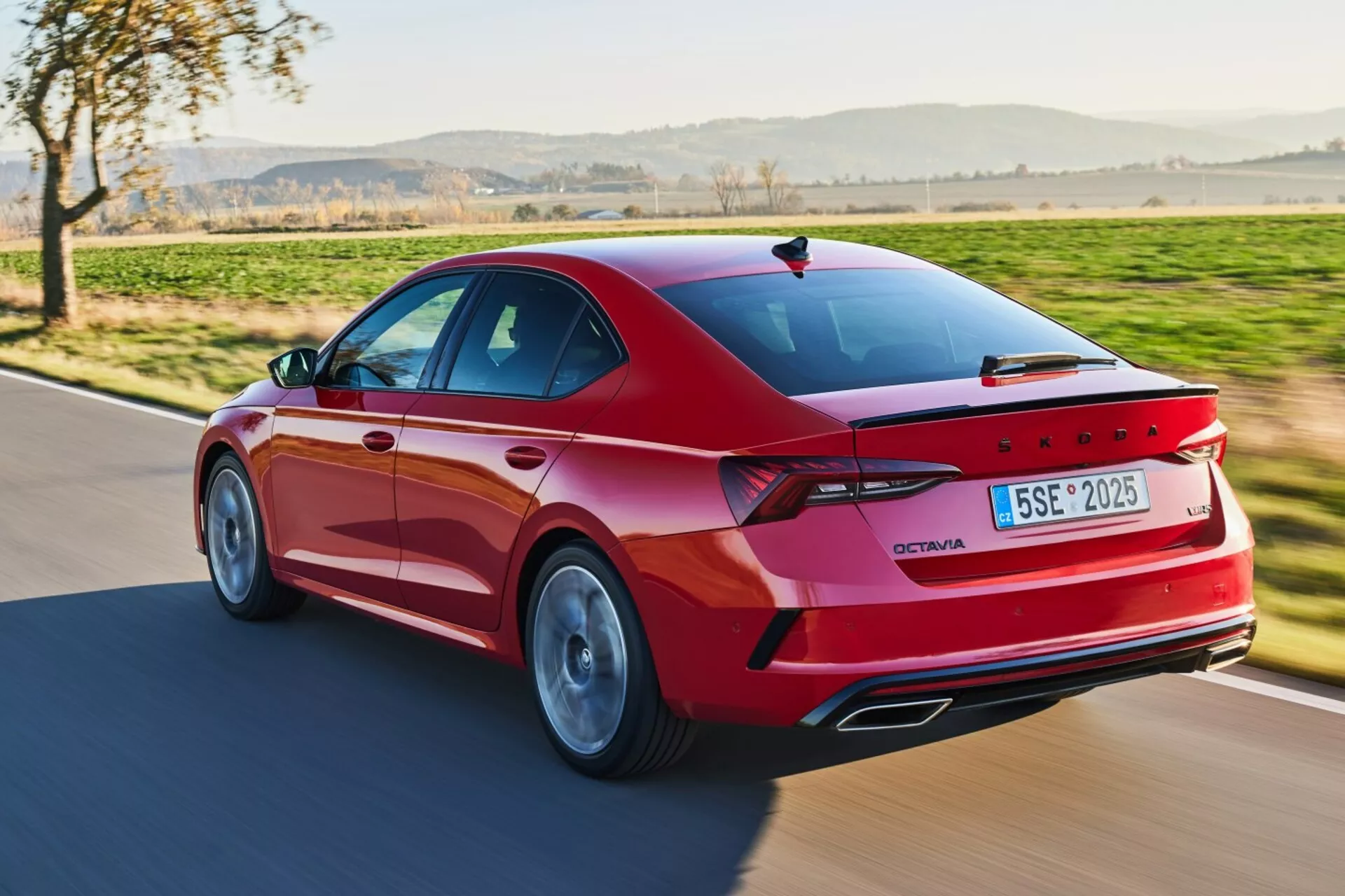 Dynamický zadný trojštvrťový pohľad na červenú limuzínu Skoda Octavia z roku 2017, ktorý zdôrazňuje jej športový exteriér s LED zadnými svetlami, zliatinovými kolesami a pokročilými funkciami v prírodnom dennom svetle