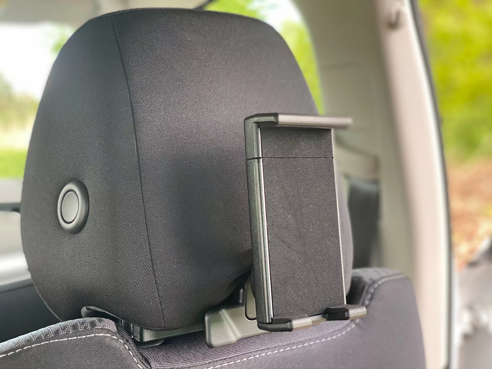 Detailný pohľad na opierku hlavy vo vozidle Škoda Octavia 2020 (Octavia-Limousine) z bočného uhla v interiéri, ktorý zdôrazňuje mechanizmus nastavovania opierky hlavy a držiak na kabáty. Opierka hlavy má textilný alebo kožený povrch s jemným vzorom, zameraný na pohodlie a dizajn.