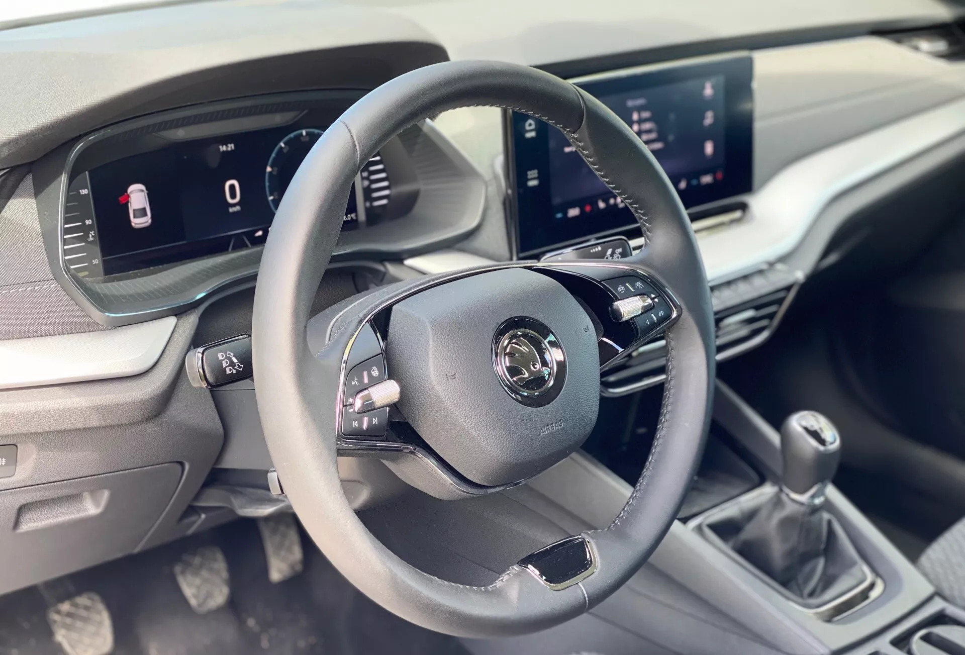 Interiér Škoda Octavia 2020 limousine zameraný na oblasť vodiča s trojramenným koženým volantom s ovládacími tlačidlami, digitálnym prístrojom a centrálnym infotainment systémom z pohľadu predného pasažiera.