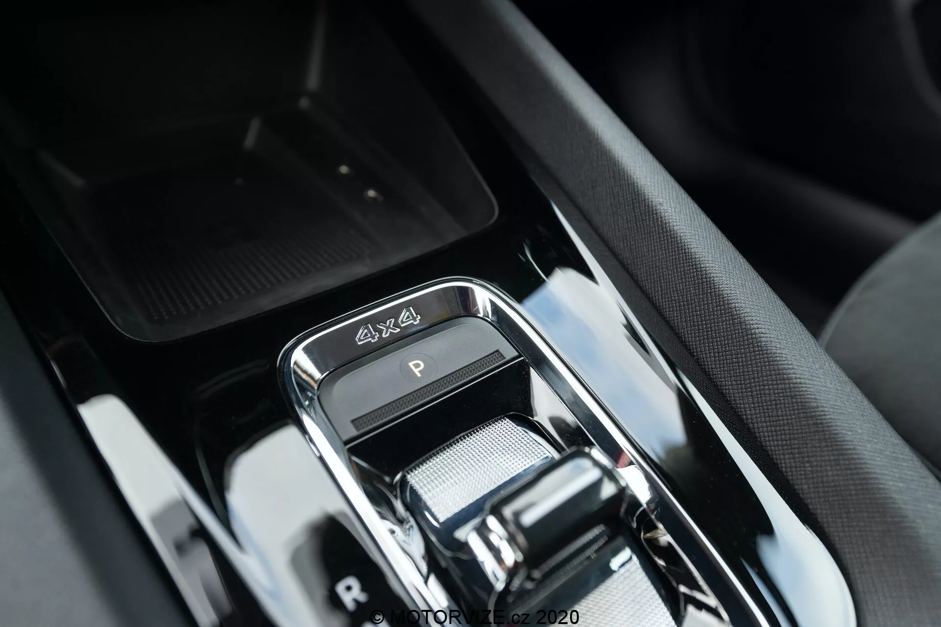 Detailný záber na prevodovku v luxusnom interiéri Škoda Octavia Scout 2020, zobrazujúci moderné elektronické radiace páku s chrómovým povrchom, emblémom 4x4, elegantným lesklým čiernym dekorom a sofistikovaným dizajnom stredovej konzoly s okolnými tlačidlami a naznačeným úložným priestorom.