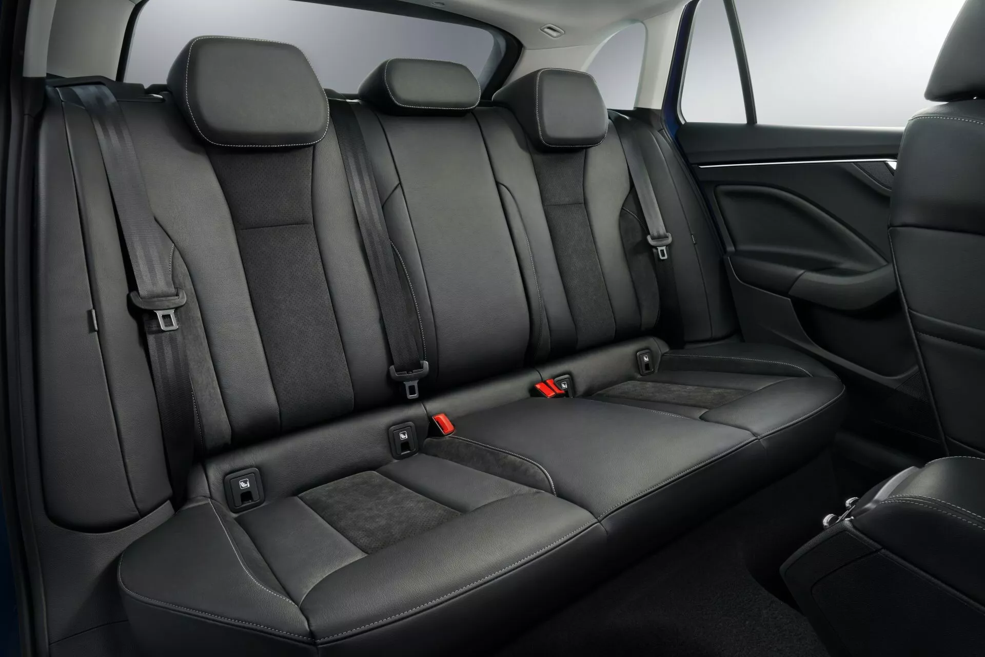 Interiér Škoda Scala 2019 s čiernymi koženými zadnými sedadlami s individuálnymi opierkami hlavy, bodmi ISOFIX, trojbodovými bezpečnostnými pásmi s červenými uvoľňovacími tlačidlami, sklopnou opierkou a priechodnou schopnosťou pre extra úložný priestor, spolu s modernými funkciami bezpečnosti a pohodlia vozidla.