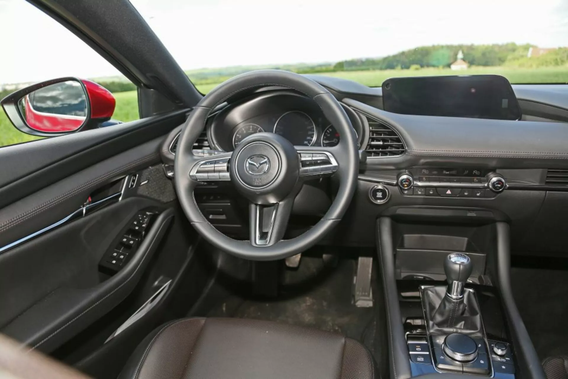 Pohľad na interiér Škoda Scala 2019 zo zadného sedadla s dôrazom na palubnú dosku, volant, stredovú konzolu, manuálnu radicu páku a dizajn prednej kabíny s technologickými a komfortnými vlastnosťami.