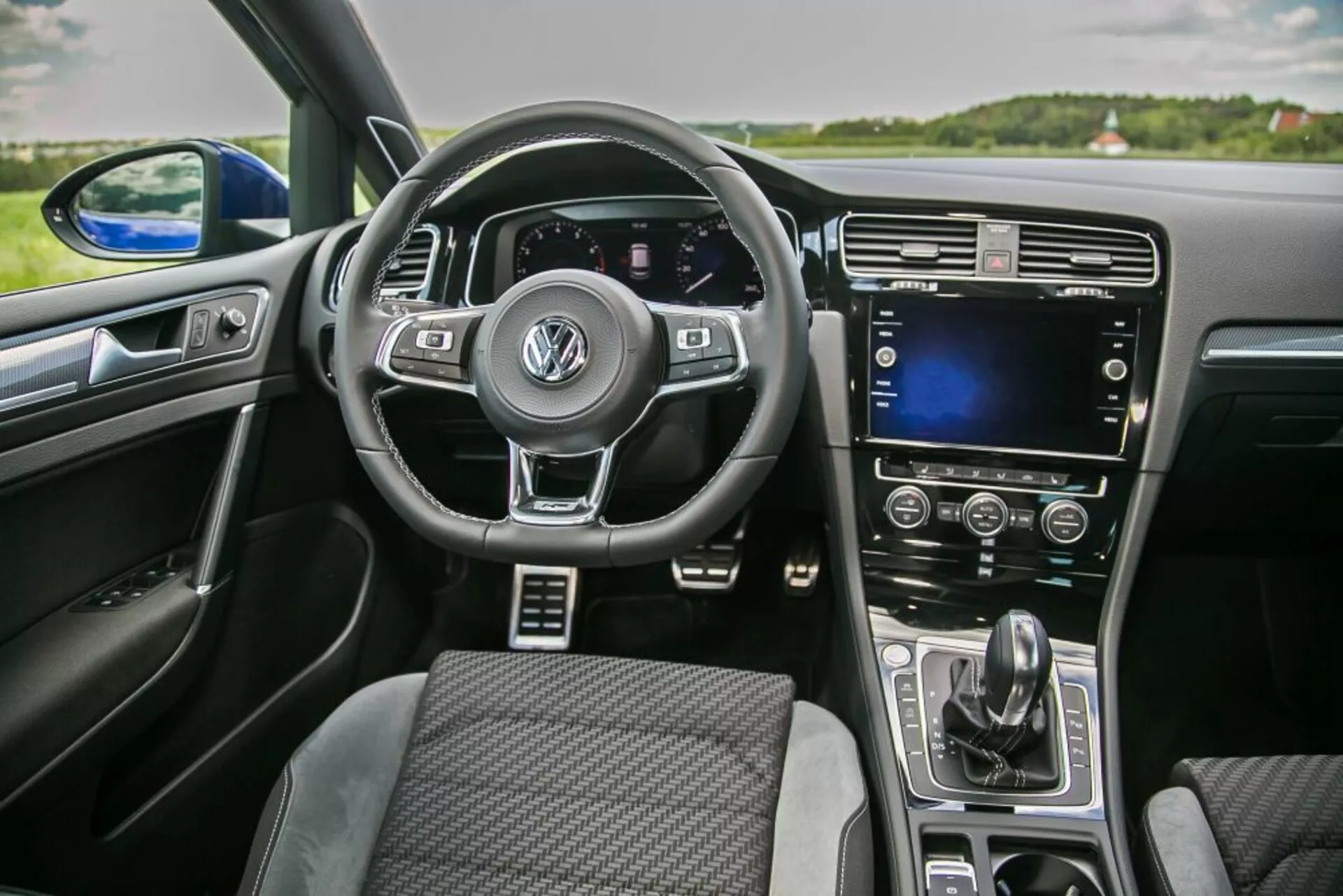Interiérový pohľad na Skoda Scala 2019 z perspektívy predného spolujazdca zahŕňajúci multifunkčný volant s logom Volkswagen, digitálny prístrojový panel, dotykovú obrazovku na stredovej konzole a automatickú klimatizáciu