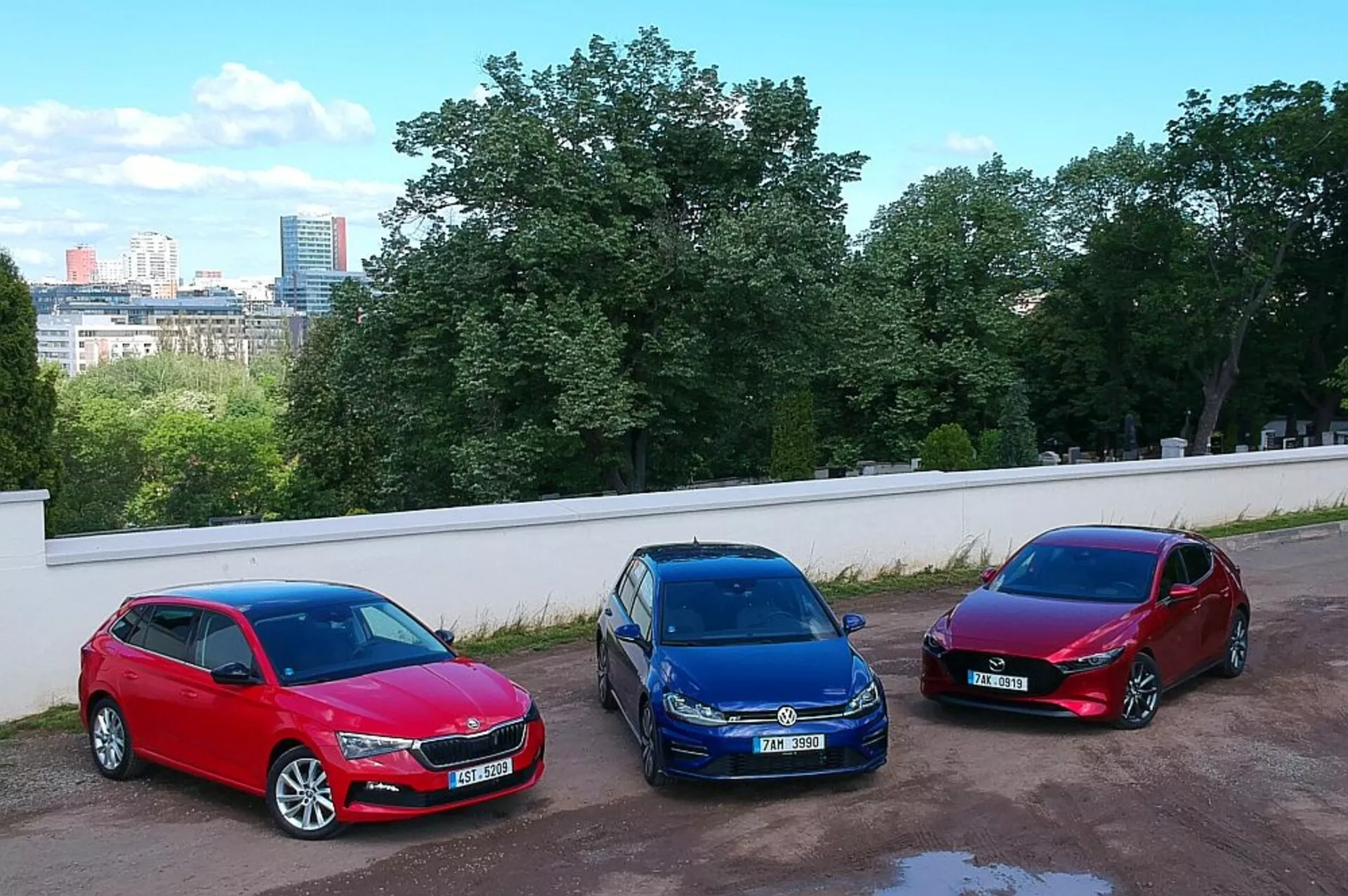 Hatchbacky Škoda Scala 2019 zaparkované vedľa seba v mestskom prostredí, predvádzajúce farby červená, modrá a burgundská s vysokým uhlom záberu z vyvýšenej pozície, zdôrazňujúce ich zliatinové kolesá, halogénové svetlomety a aerodynamické dizajny