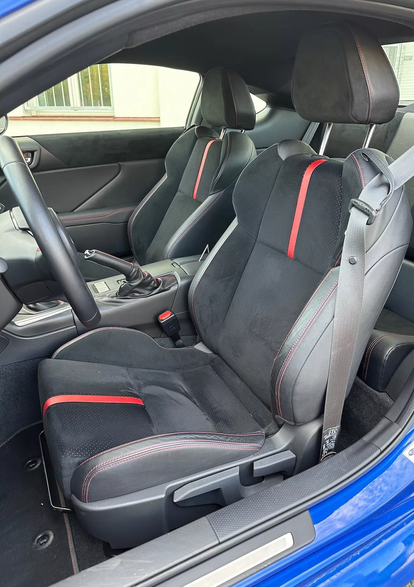 Interiér Subaru BRZ 2023 s dôrazom na športové predné sedadlá s ergonomickým dizajnom a červenými detailmi, volič automatickej prevodovky a modernú estetiku kokpitu zo šikmého vonkajšieho pohľadu