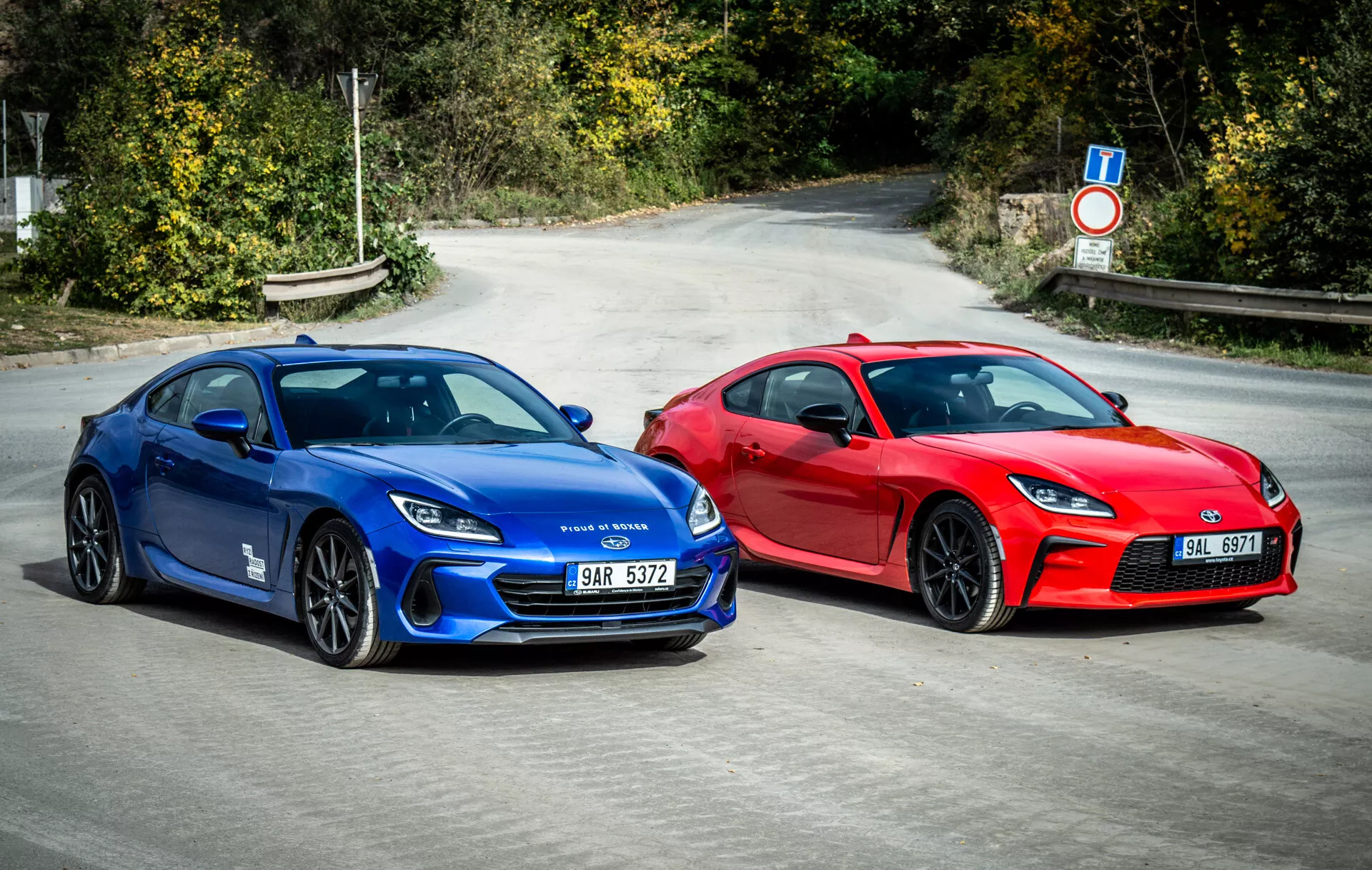 Dvojica Subaru BRZ 2023 predvádzajúca športové autá v štýle kupé vo výraznej modrej a pôsobivej červenej farbe zaparkované vedľa seba na asfalte s aerodynamickými dizajnovými prvkami, modernými LED svetlometmi a kolami orientovanými na výkon pod prirodzeným denným svetlom
