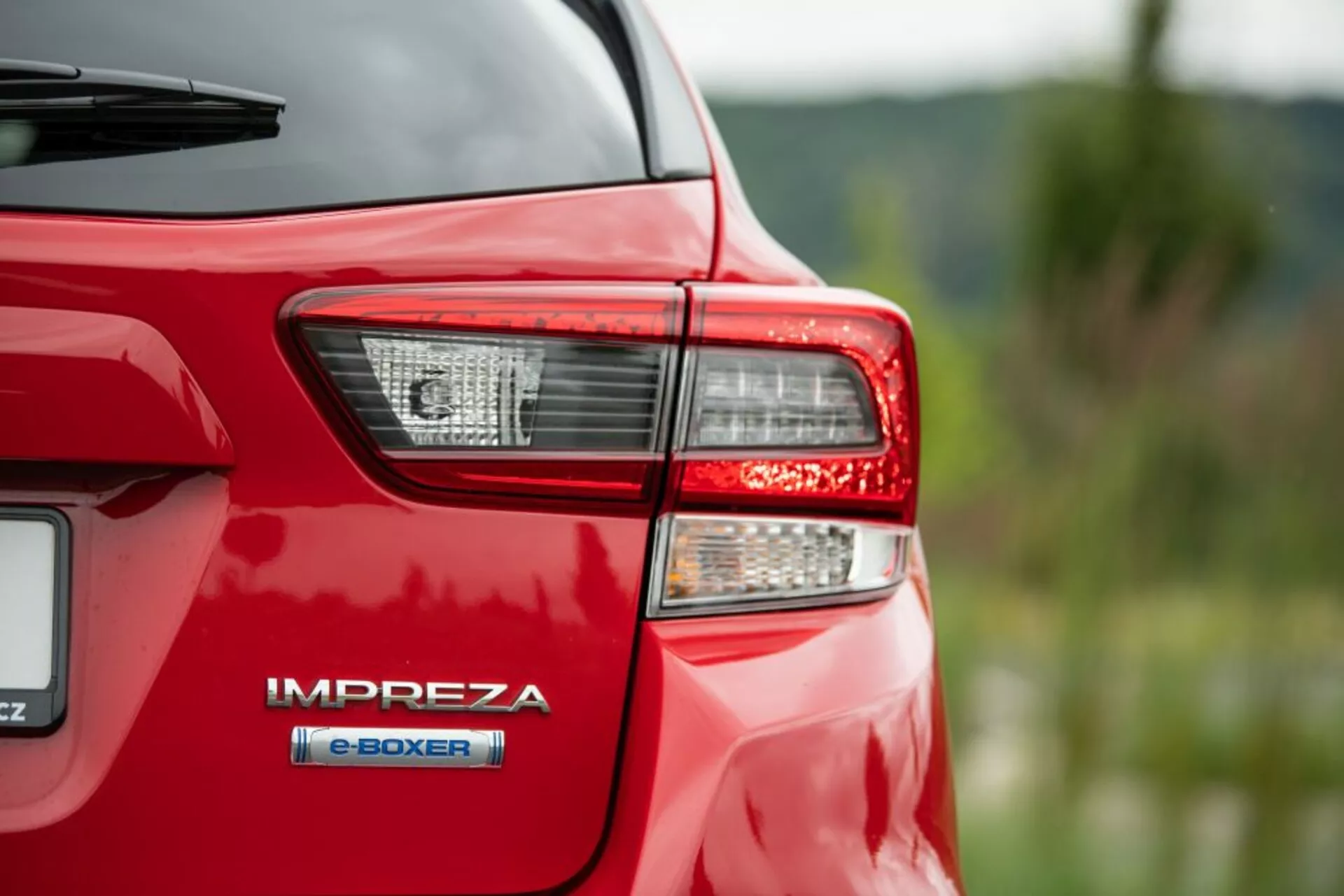 Detailný pohľad na zadnú ľavú stranu červeného Subaru Impreza z roku 2018 s detailne prepracovanou súpravou zadných svetiel s technológiou LED a odznakom hybridného pohonu e-BOXER