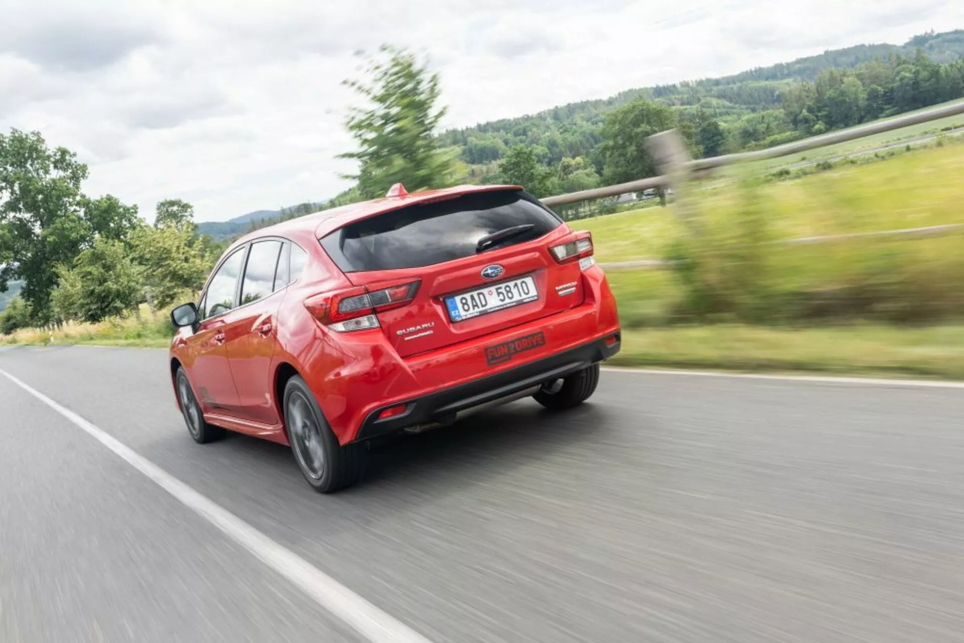 Subaru Impreza 2018 vo vibrantnej červenej farbe, ktorá prezentuje moderný dizajn s aerodynamickým zadným spoilerom a dvojitým výfukom, zachytená z uhla tri štvrtiny zadnej časti, čo zdôrazňuje rýchlosť a dizajnové čiary.
